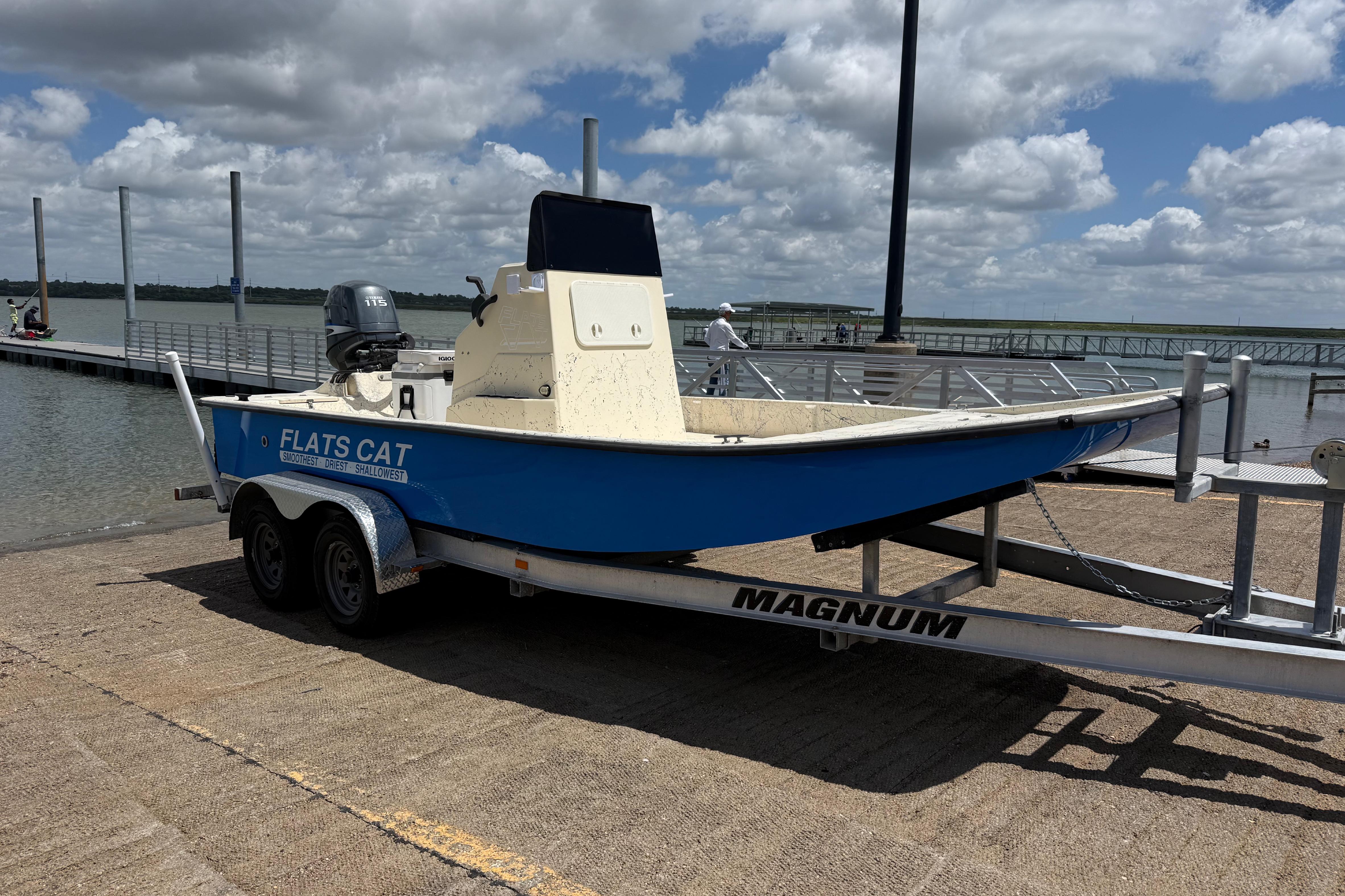 2007 Flats Cat 19 boat on trailer by a dock under a cloudy sky.