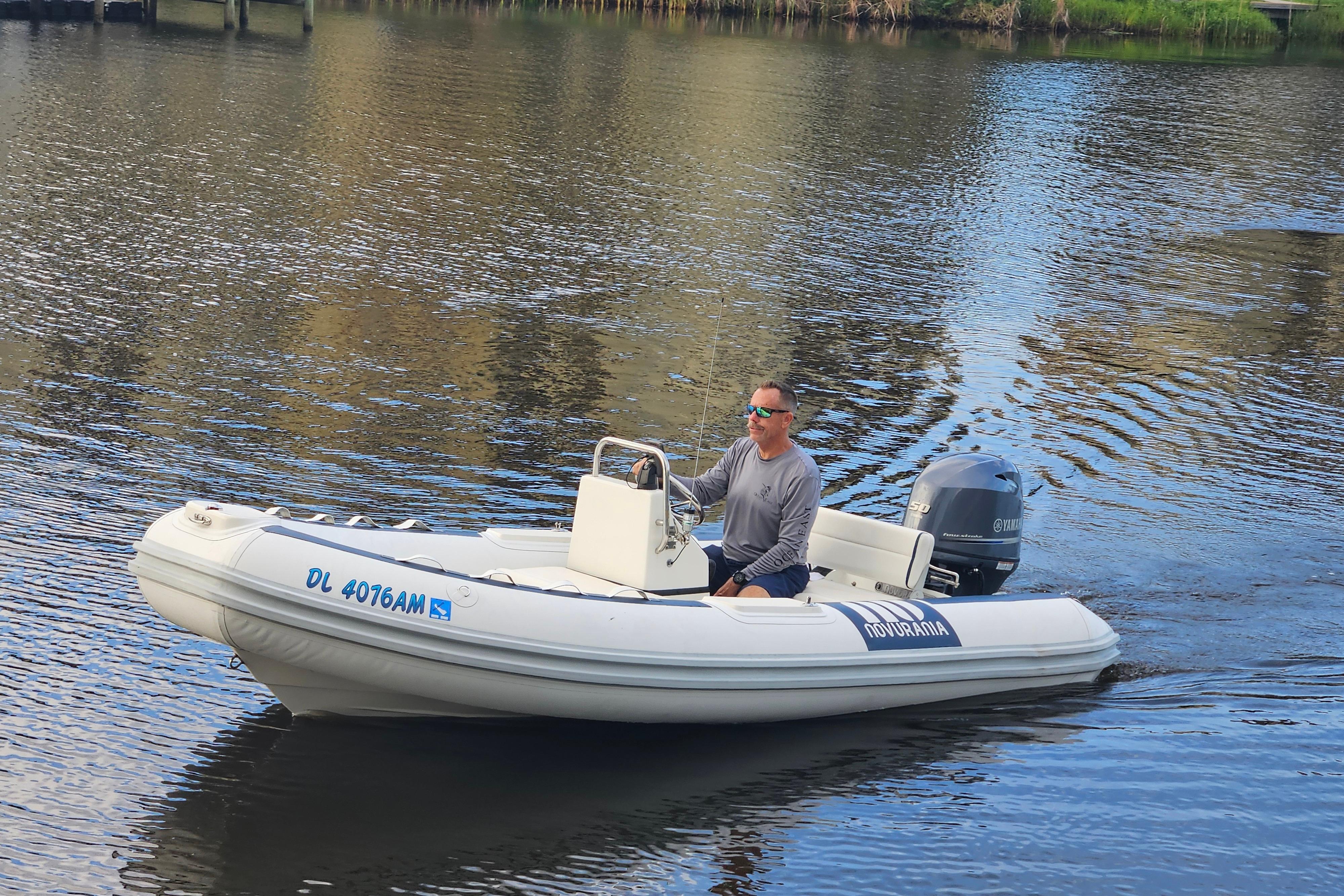2019 Novurania DL 400 boat on calm water, man steering, Yamaha engine visible.