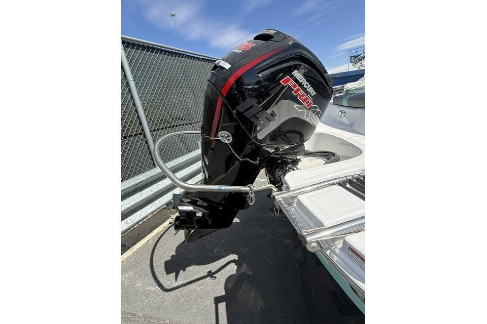 2026 Tahoe T18 boat with Mercury Pro XS outboard motor, parked near a chain-link fence.