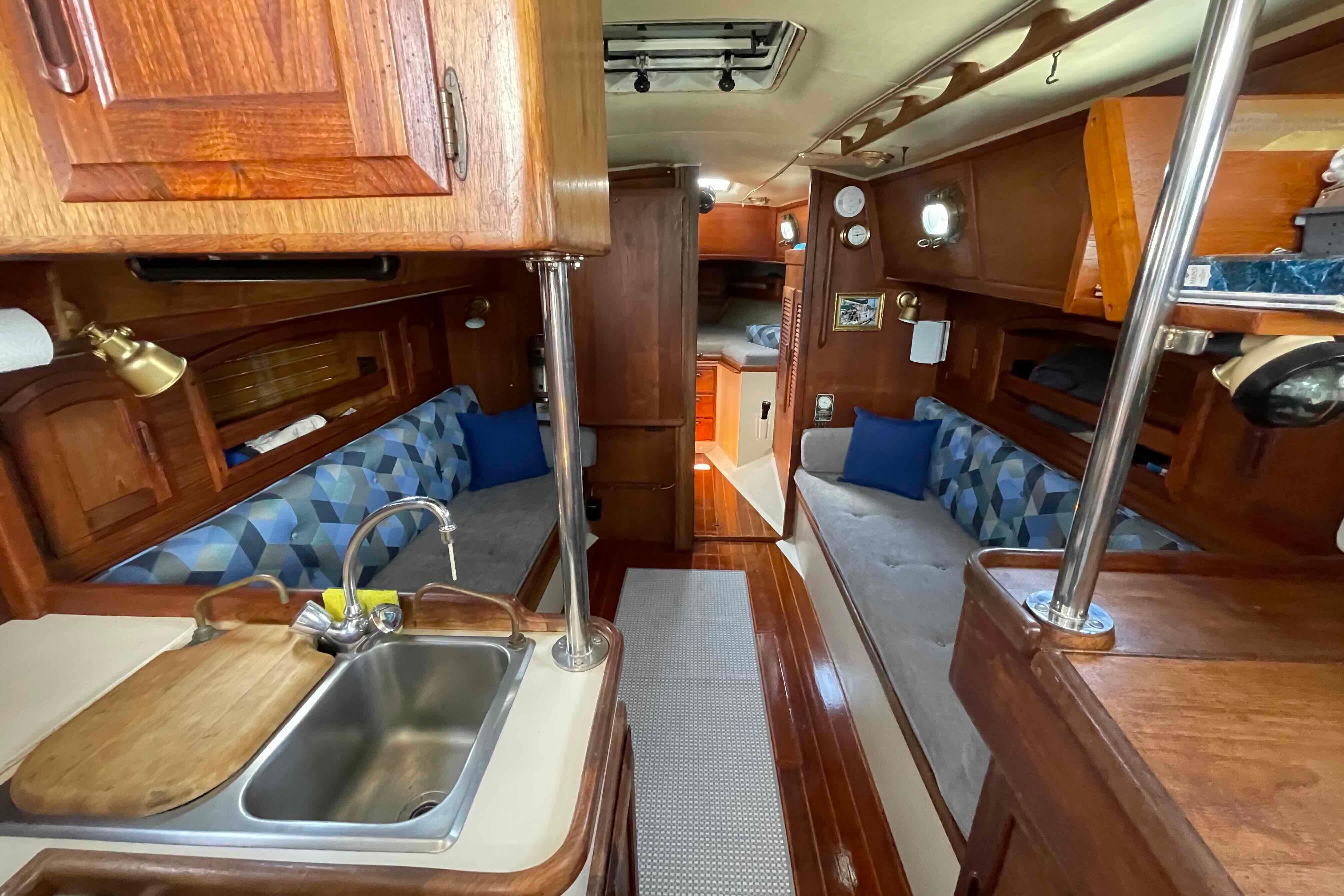 1987 Pacific Seacraft 34 interior with cozy seating, wooden cabinetry, and compact kitchen area.
