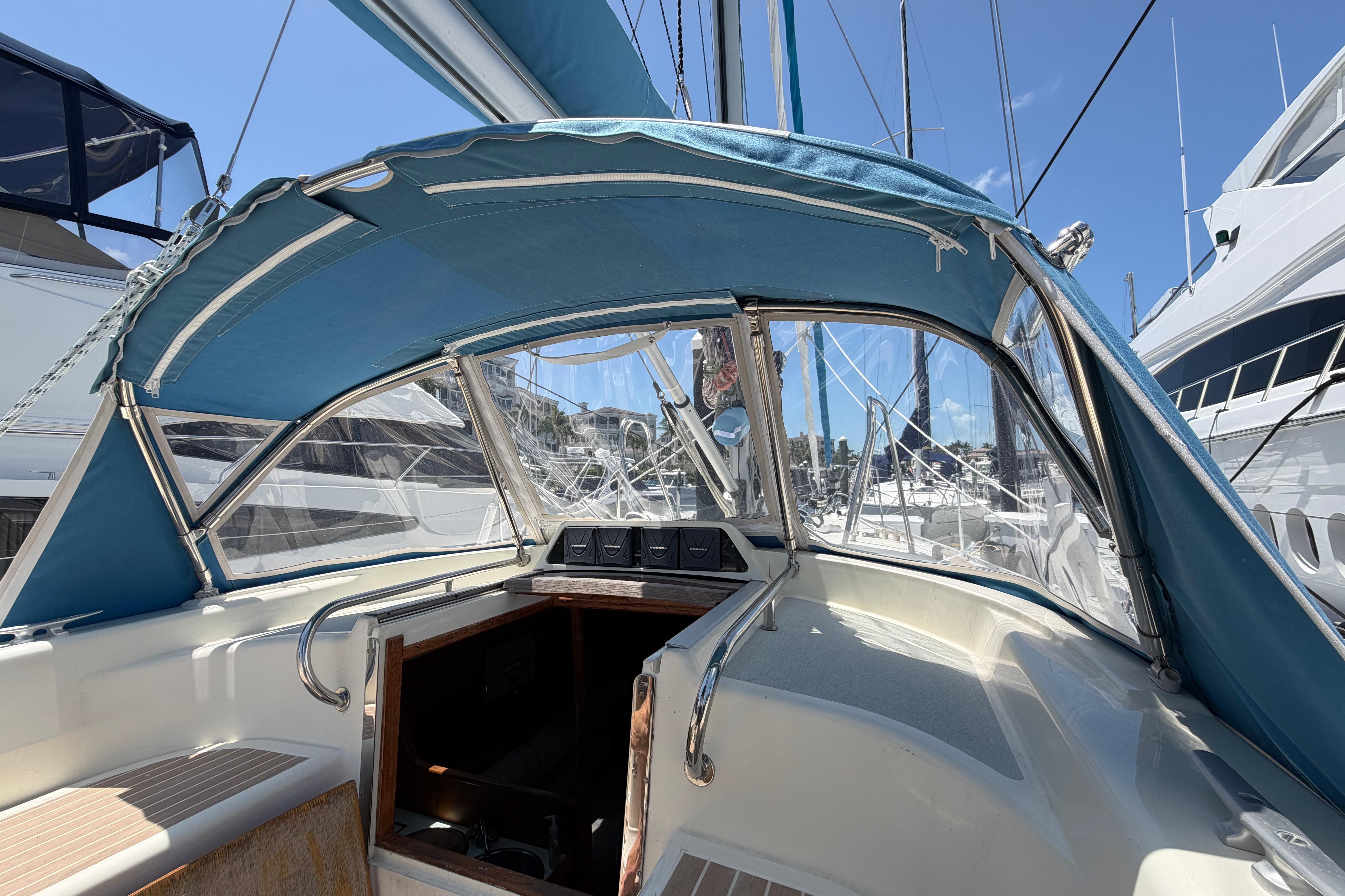 Cockpit view of a 1987 Moody 376 sailboat with blue canopy in a marina.