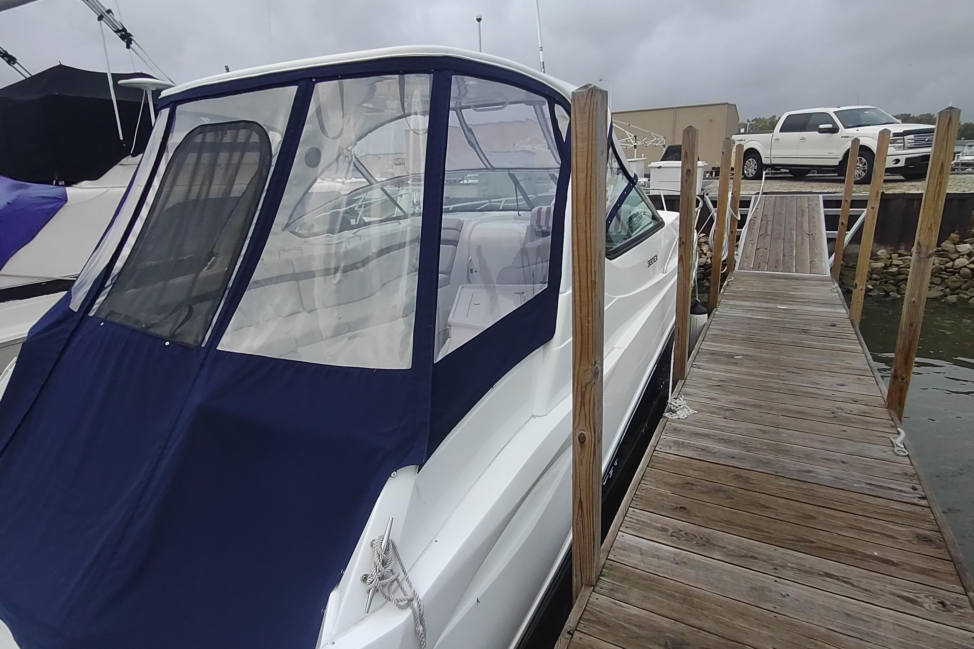 2017 Rinker EX 320 boat docked beside wooden pier under cloudy sky.