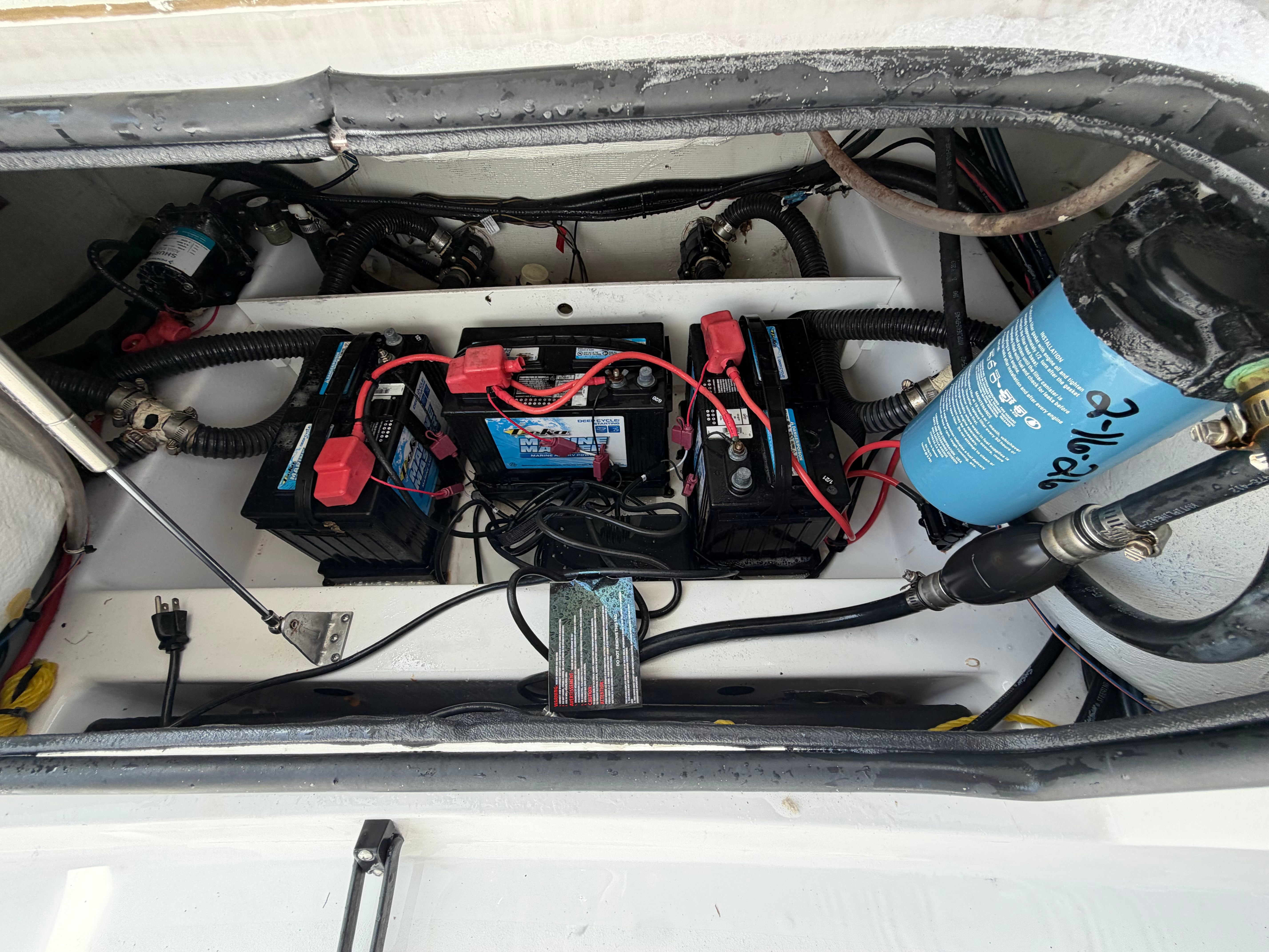 Batteries and wiring in a boat's engine compartment, neatly arranged with blue filters.
