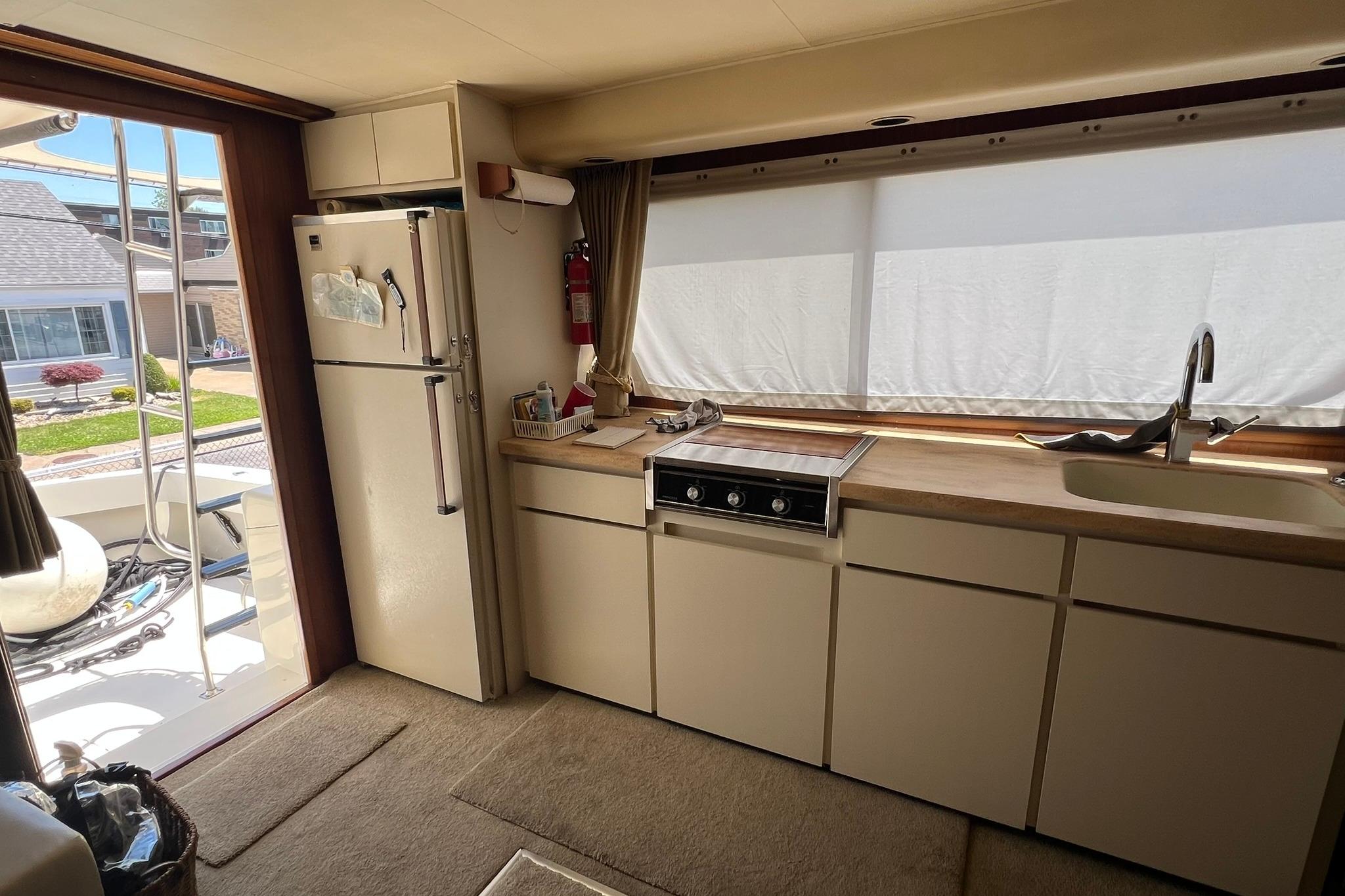 Interior of 1990 Hatteras 41 Convertible yacht kitchen with appliances and window view.