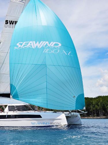 2025 Seawind 1160 XL catamaran sailing with blue spinnaker on a sunny day.