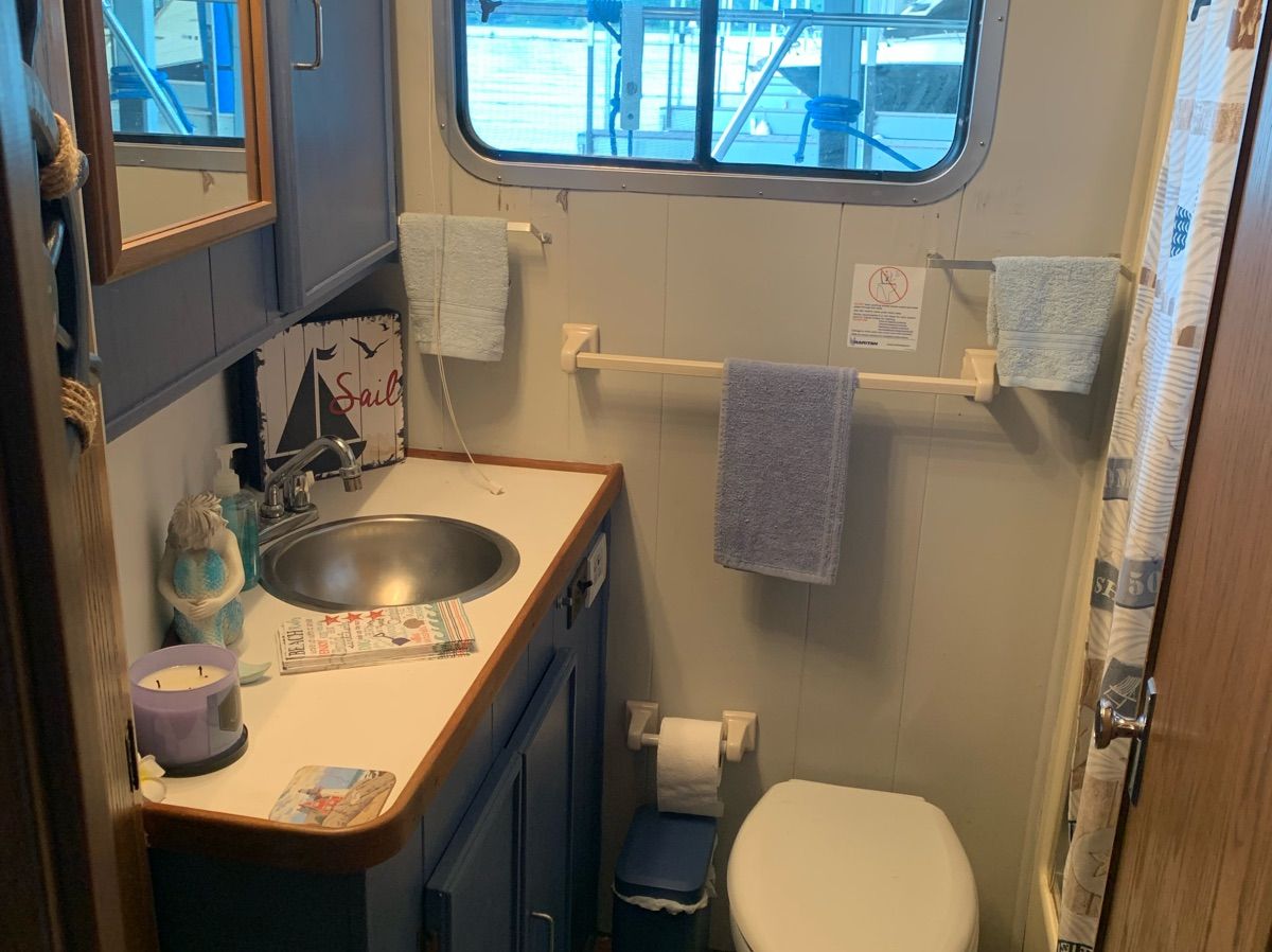 The image shows a boat bathroom with a sink, toilet, and towels.