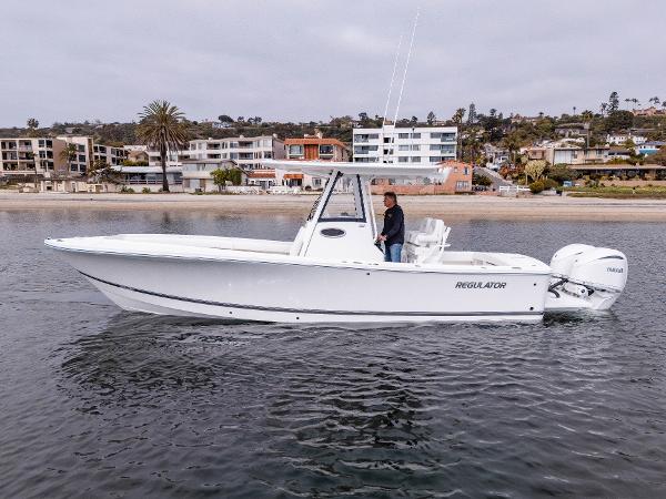 2025 Regulator 28 boat on calm water near coastal buildings.