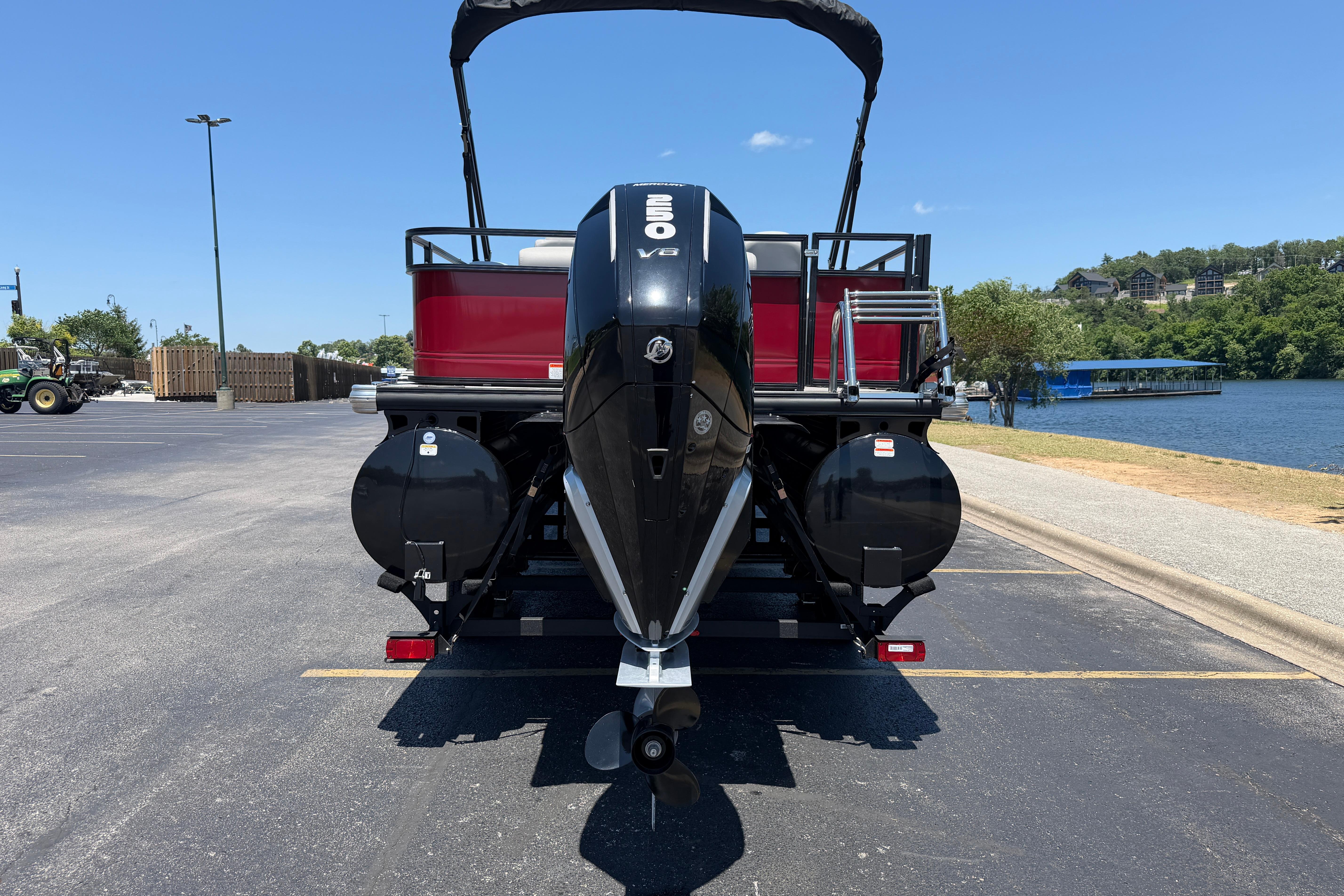 2024 Regency R250DL3 pontoon boat with powerful outboard motor, parked near a scenic lake.