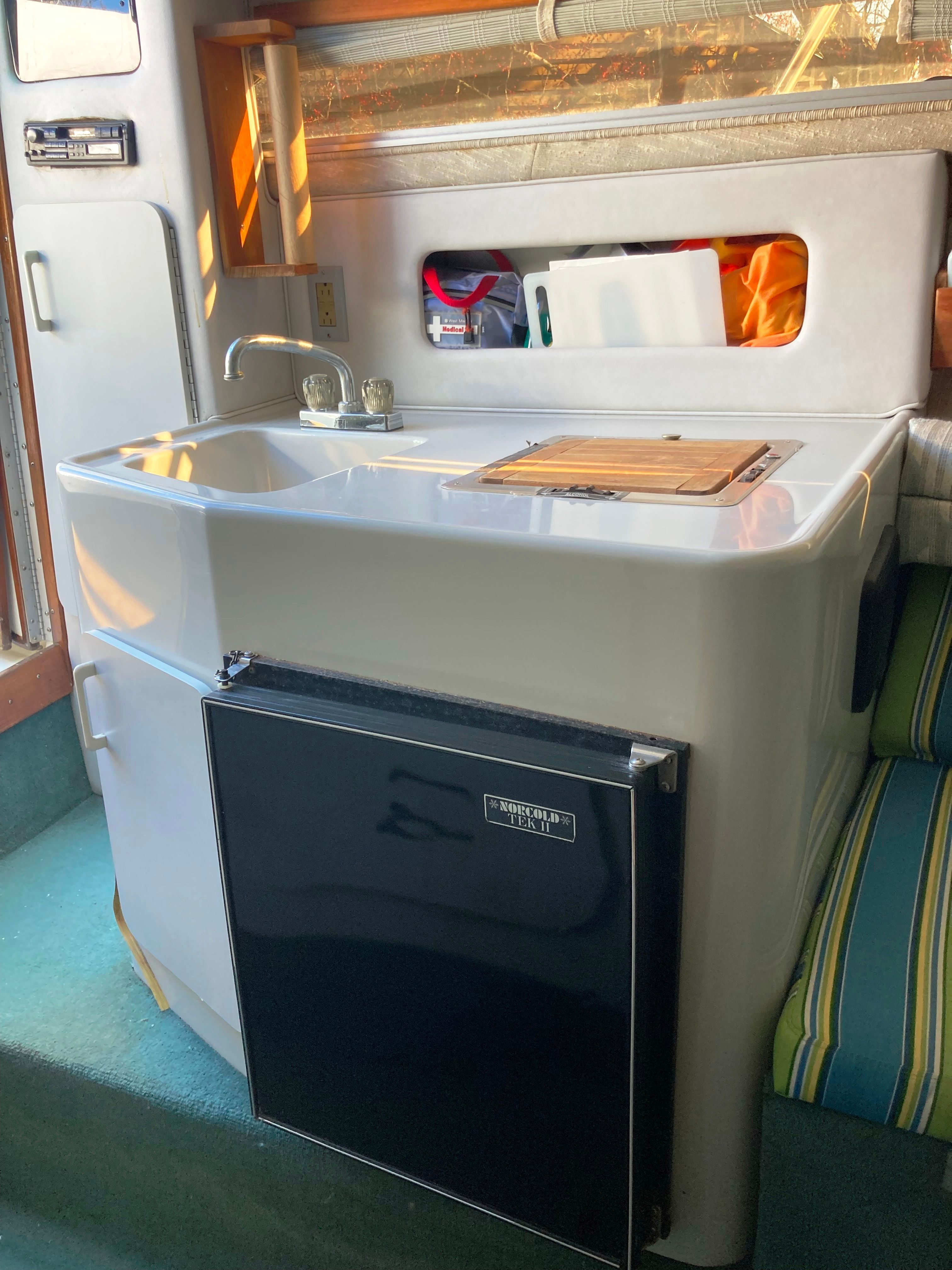 The cabin of a 1991 Sea Ray 220 Sundancer features a compact kitchenette with a sink and fridge.