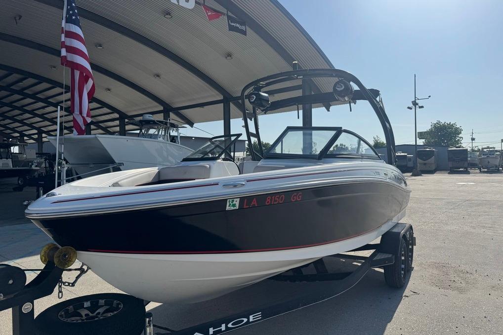 2018 Tahoe 700 TF boat on trailer, parked under a canopy with American flag.