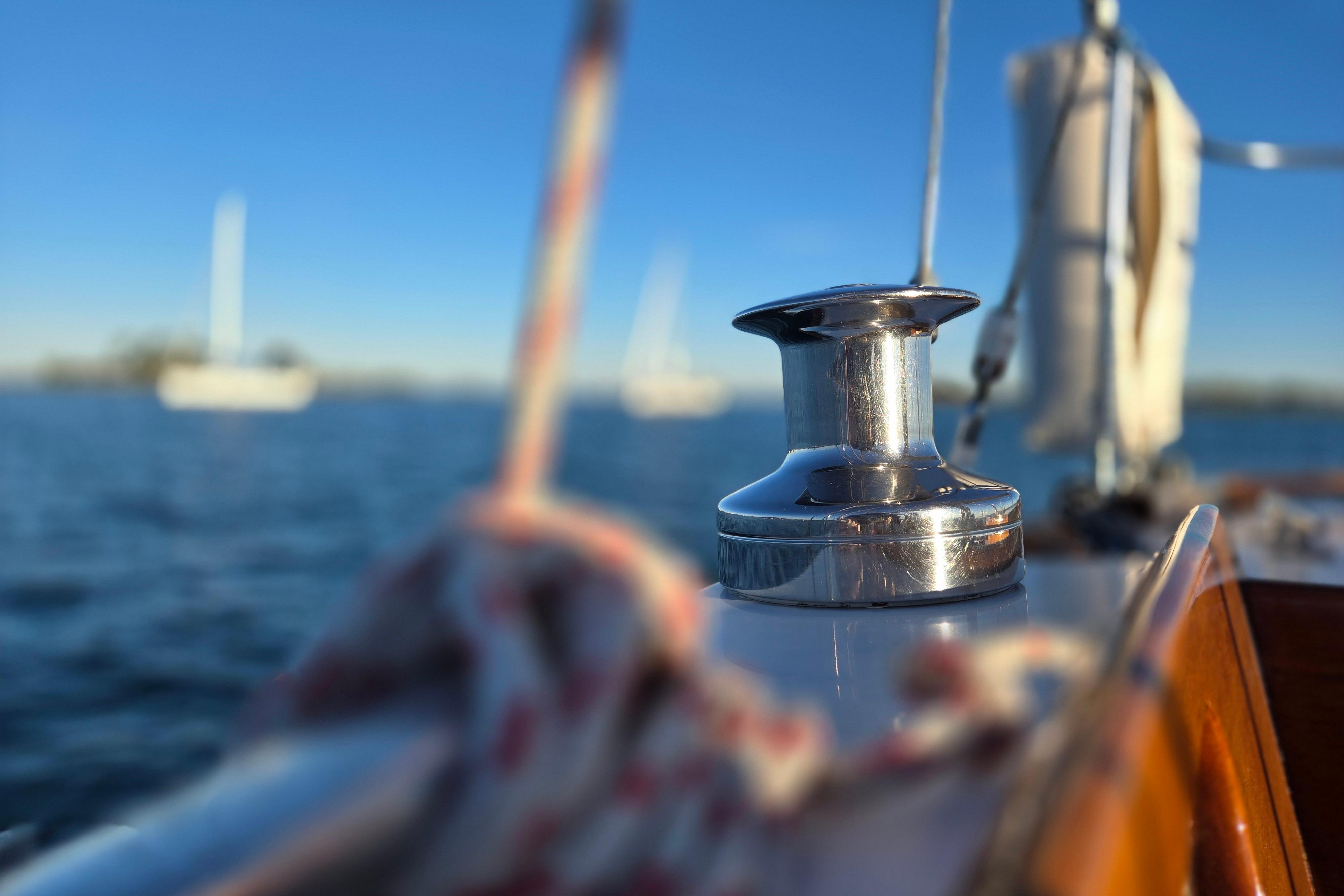 Close-up of a winch on a 1970 Hinckley Bermuda 40 sailboat, with blurred ocean background.