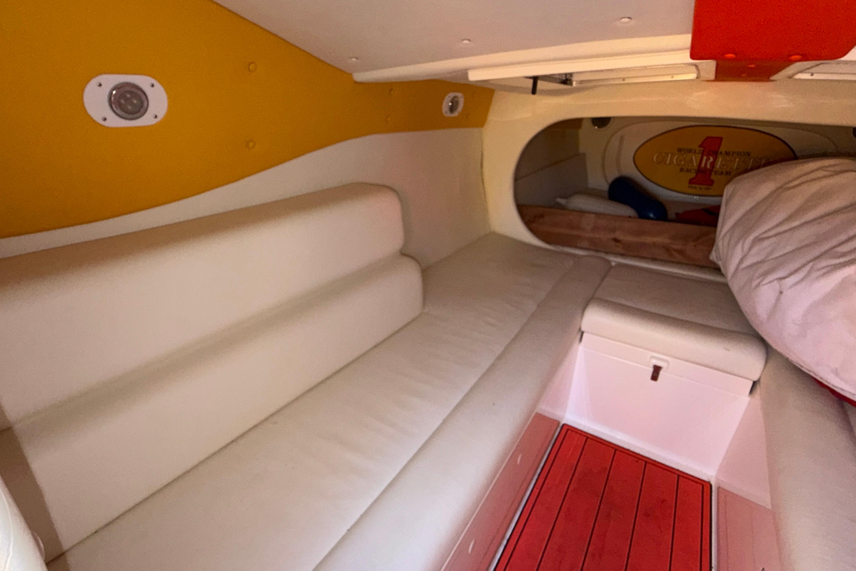 Interior cabin of a 2002 Cigarette 35' Cafe Racer boat, featuring white seating and vibrant accents.