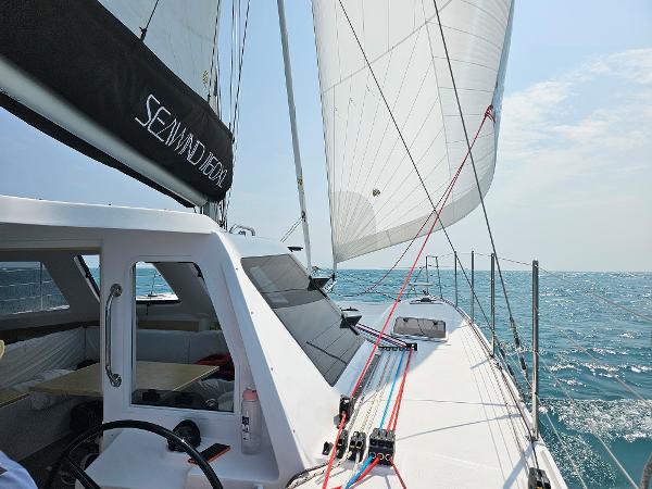 Sailing on a 2025 Seawind 1160 XL catamaran with full sails on open water.