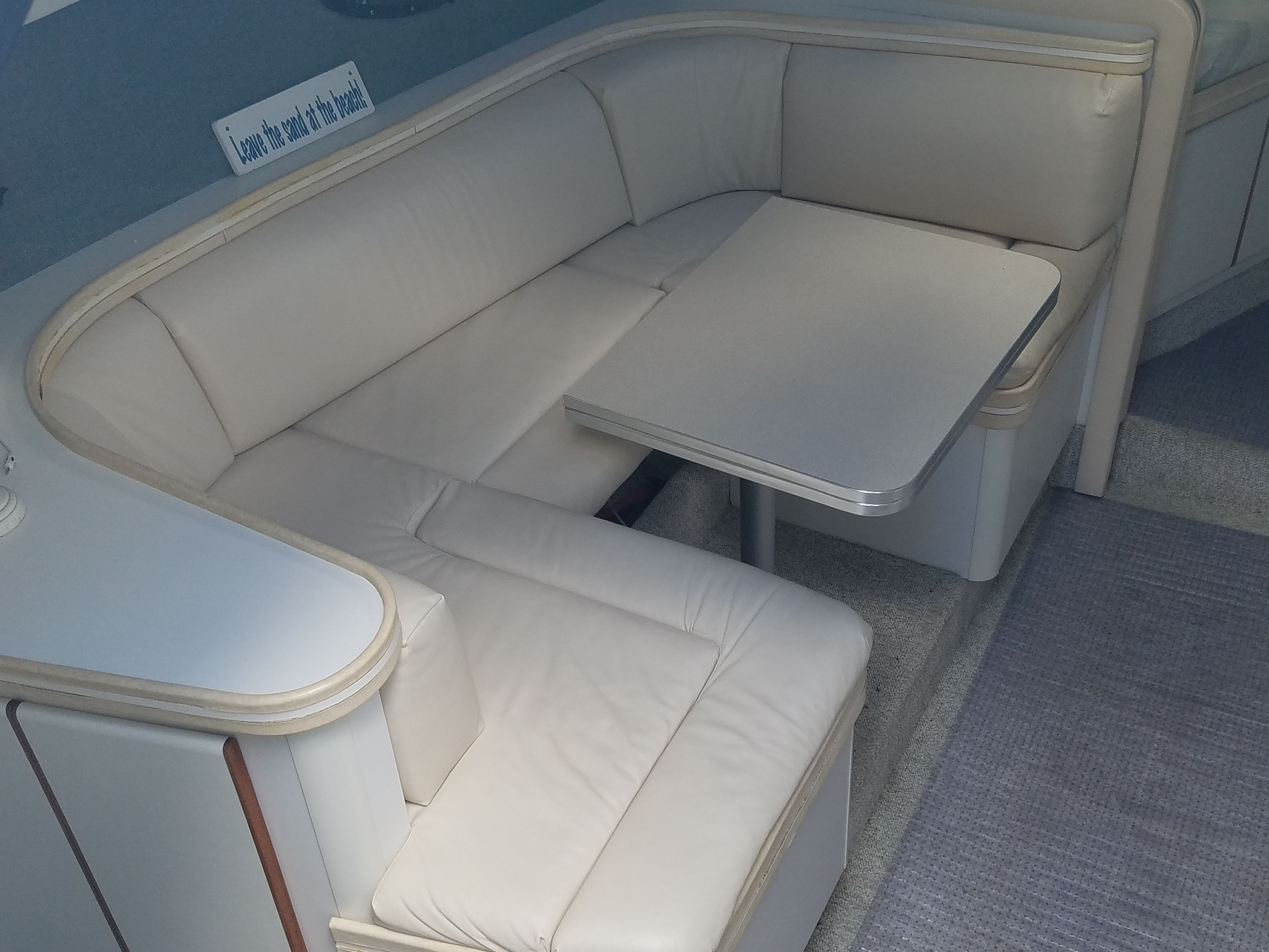 Interior of a 1989 Tiara Yachts Slickcraft with cream-colored upholstered seating and a table.
