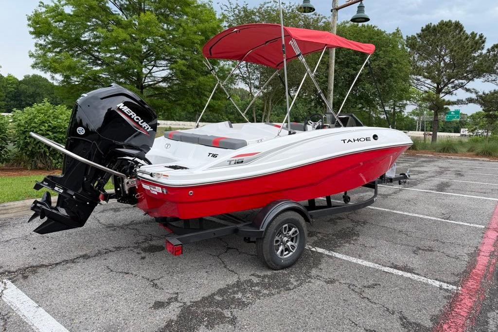 2026 Tahoe T16 boat with red hull and Mercury outboard motor in parking lot.