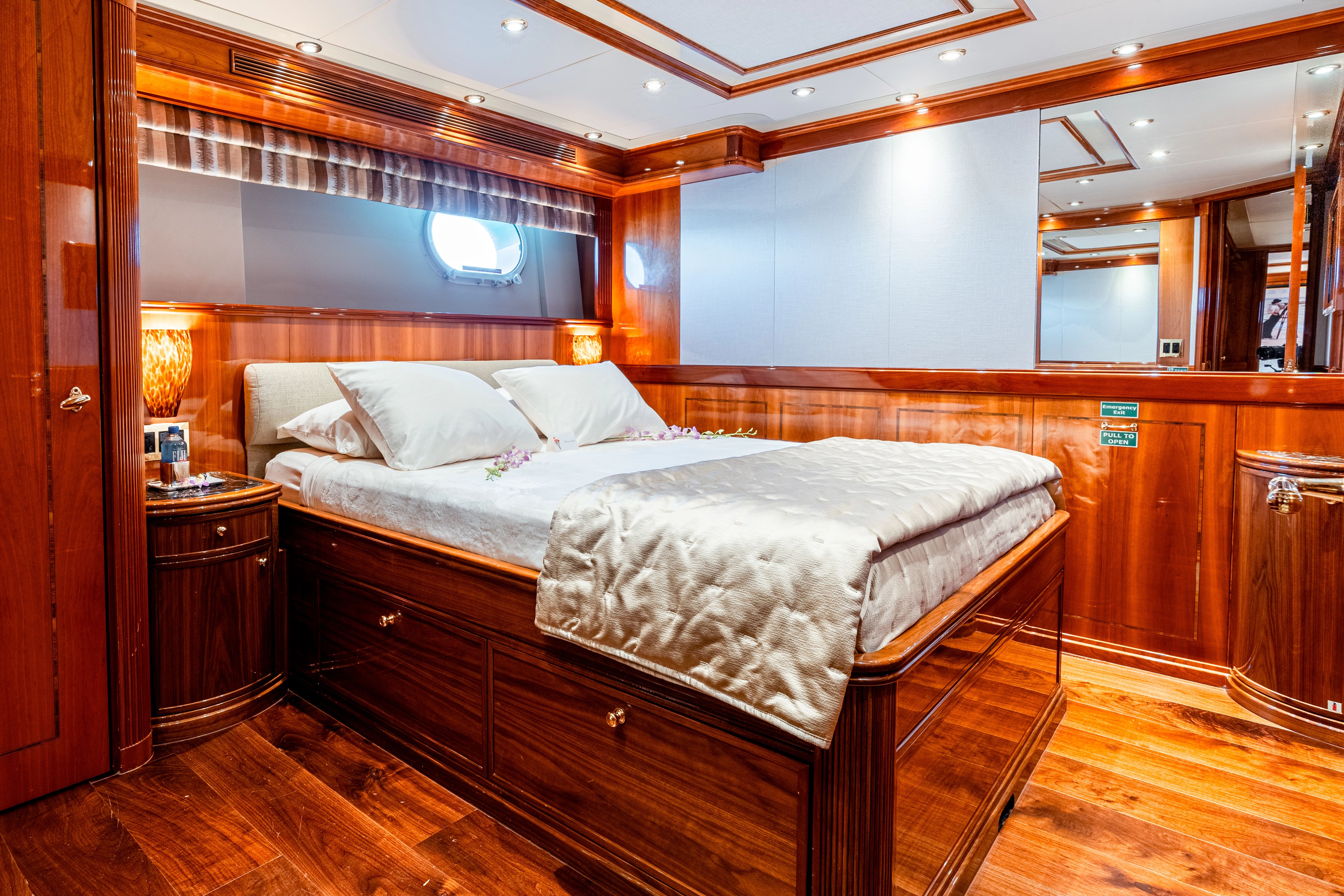Luxurious cabin with wood paneling, a large bed, and elegant lighting on a Palmer Johnson yacht.