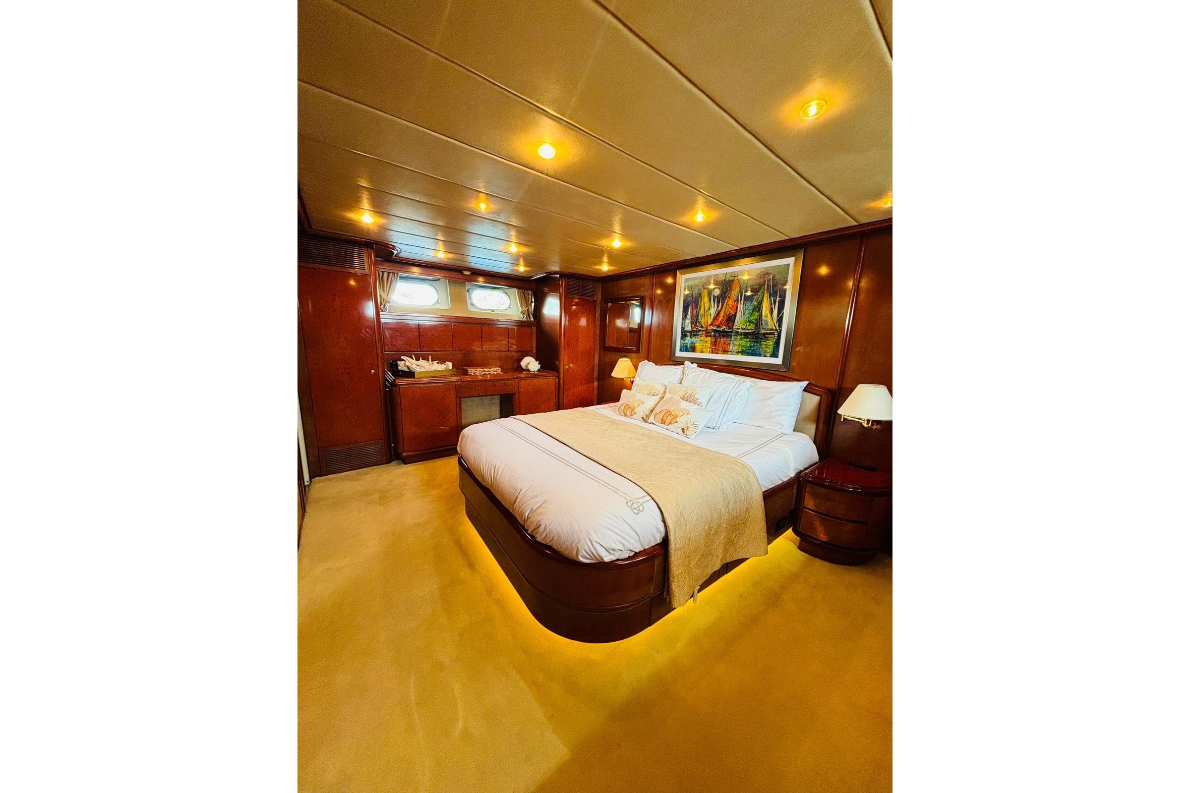 Luxurious bedroom interior on a 2000 Falcon 100 yacht, featuring elegant wood paneling and ambient lighting.