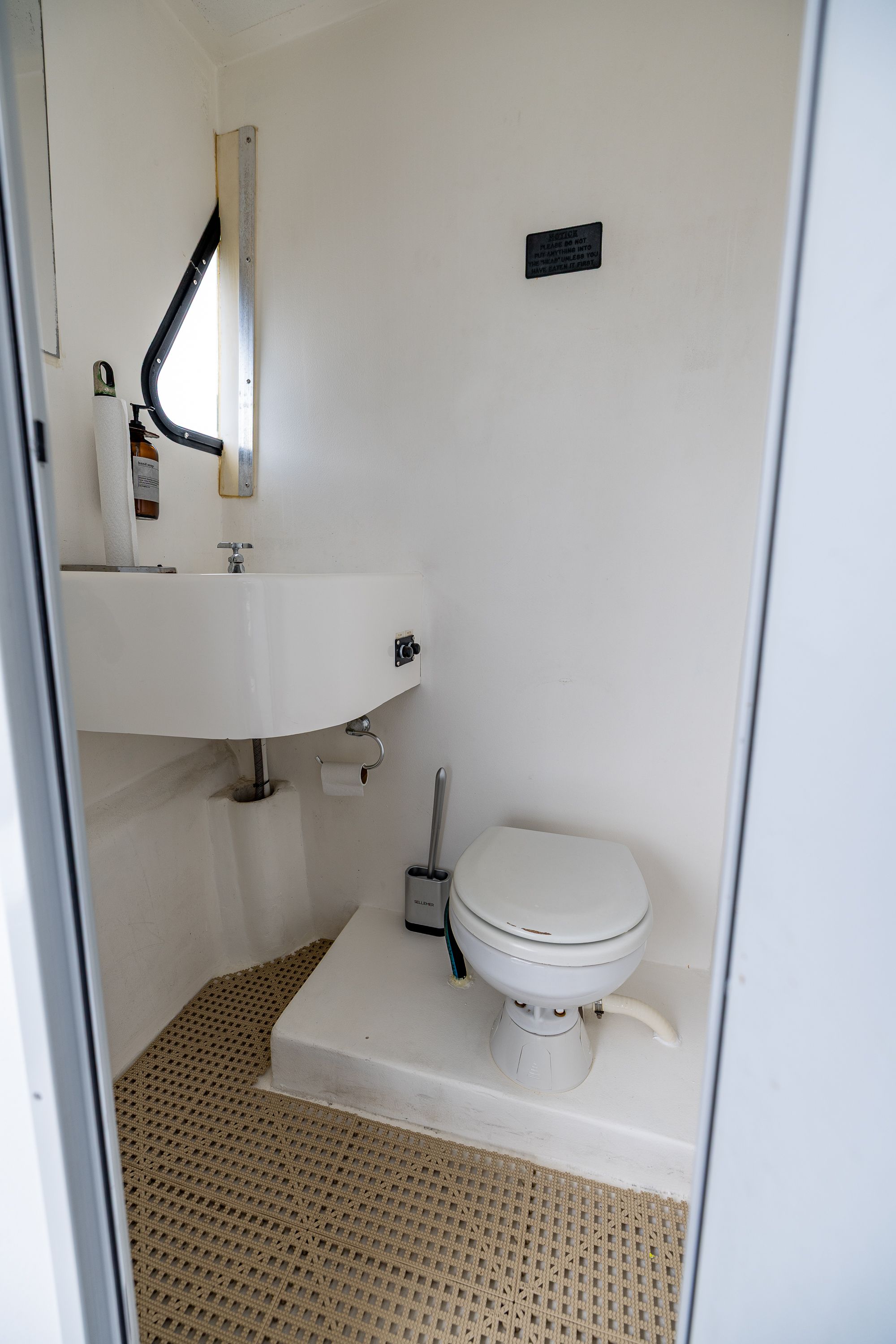 The image shows a simple boat bathroom with a toilet and sink.