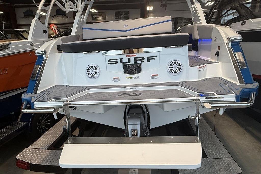 2026 Cobalt R4 Surf boat rear view in showroom, featuring swim platform and speakers.