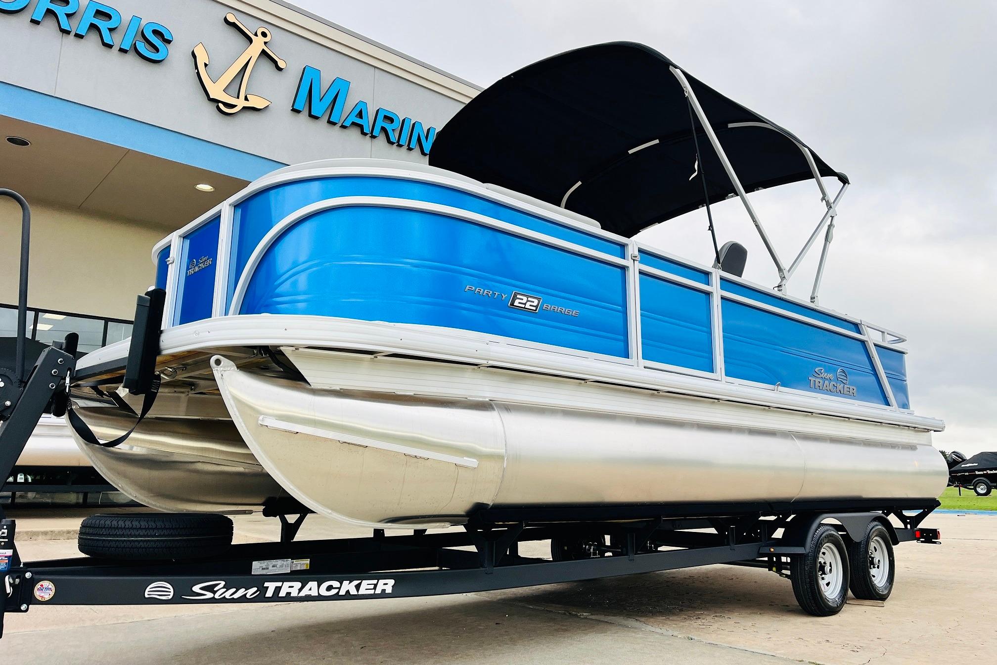 2026 Sun Tracker Party Barge 22 RF DLX pontoon boat on trailer at dealership.