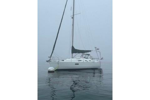 Sailboat on calm water in fog.