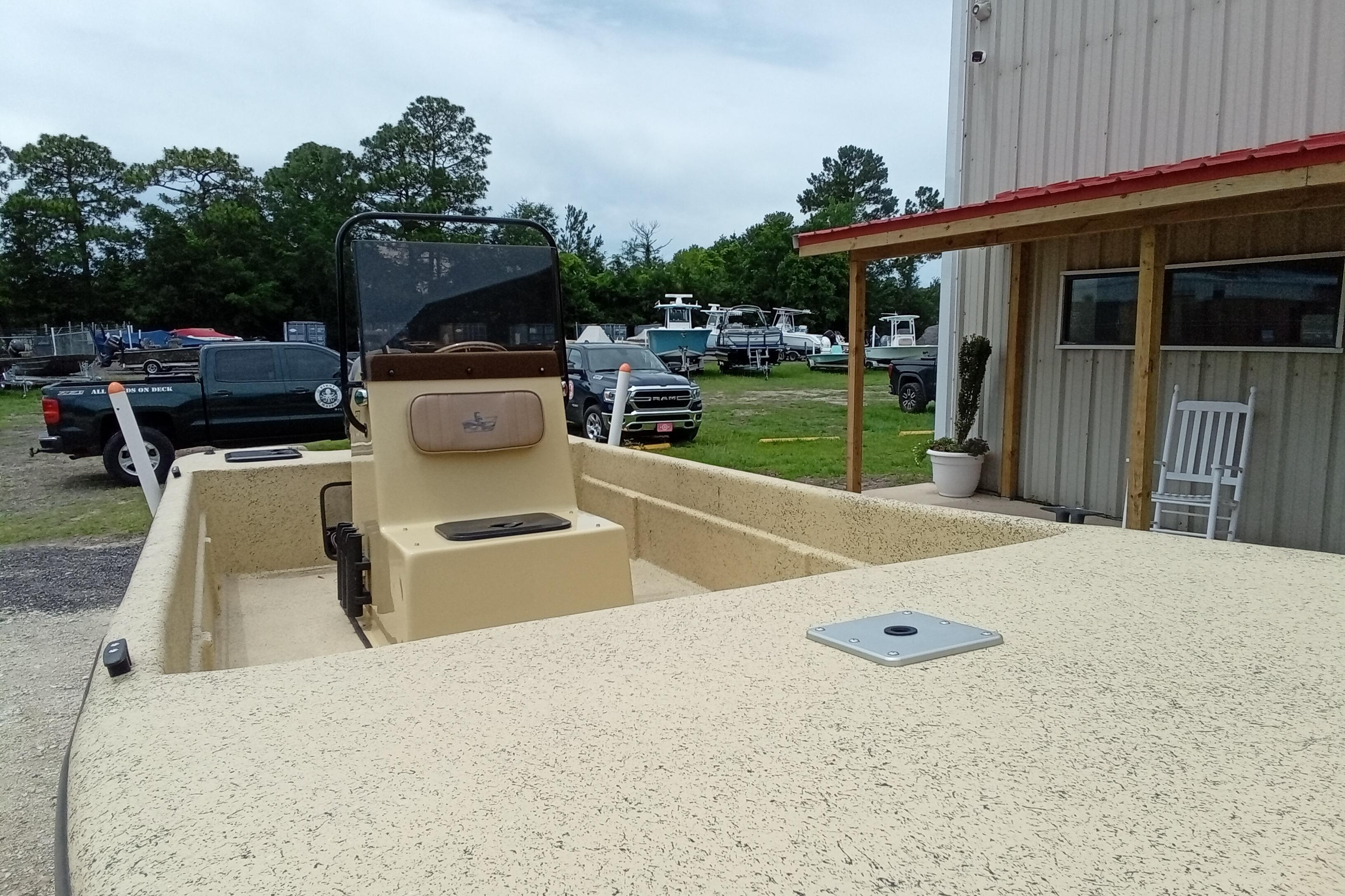 2025 Fibercraft F17 boat parked outside a building, surrounded by vehicles and trees.