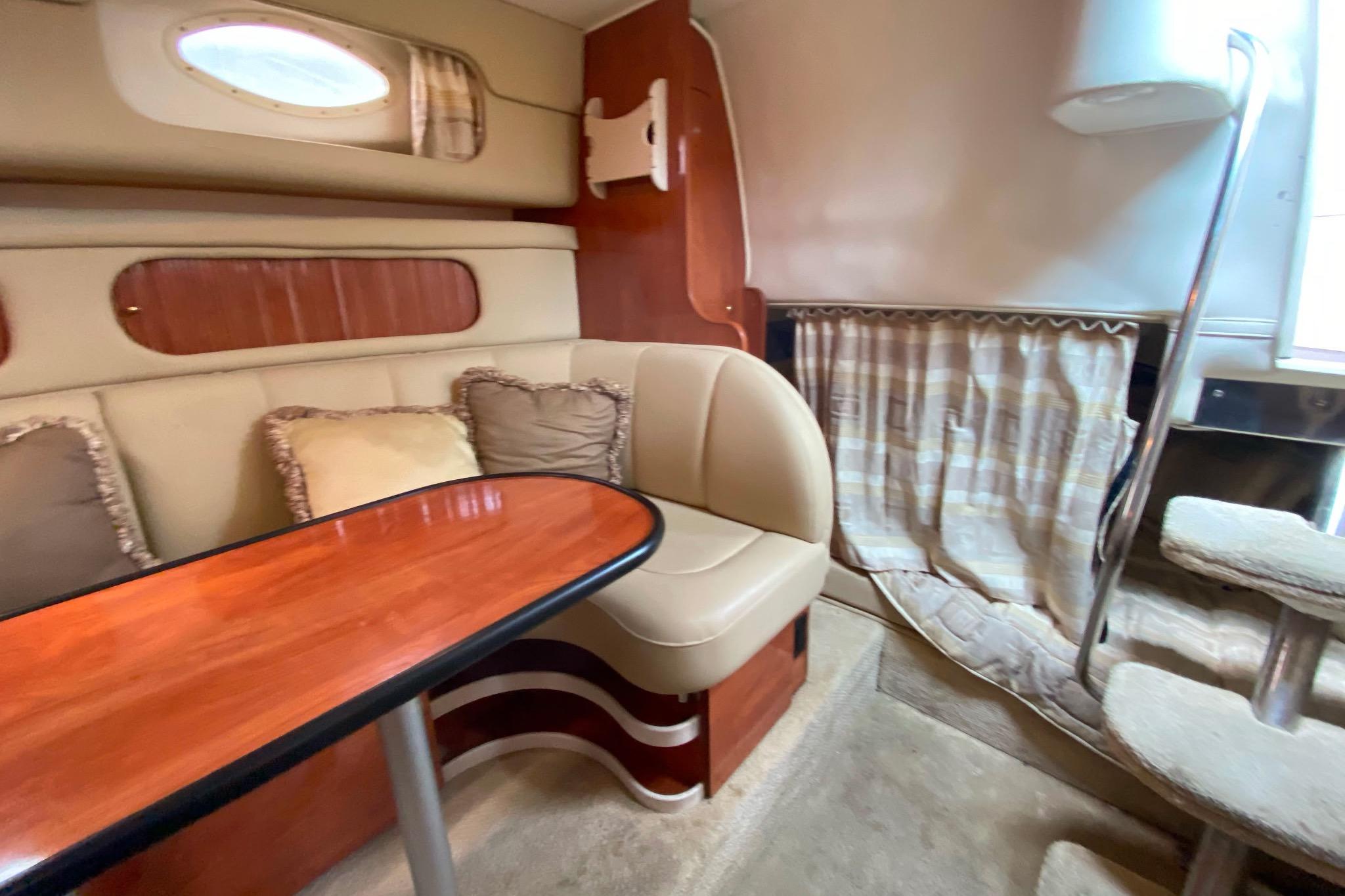 Interior of 2003 Rinker Fiesta Vee 342 boat with cozy seating and wooden table.