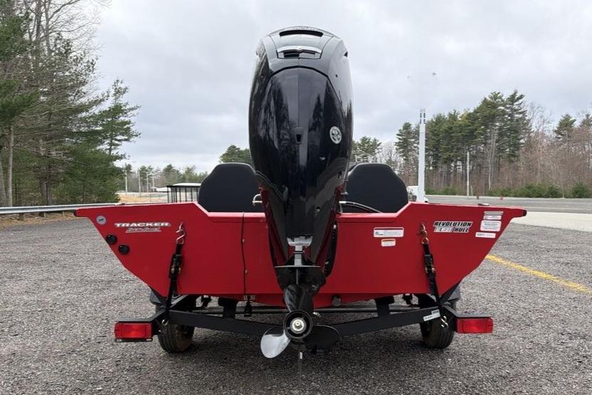 2026 Tracker Pro Team 175 boat, rear view with outboard motor, parked on gravel.