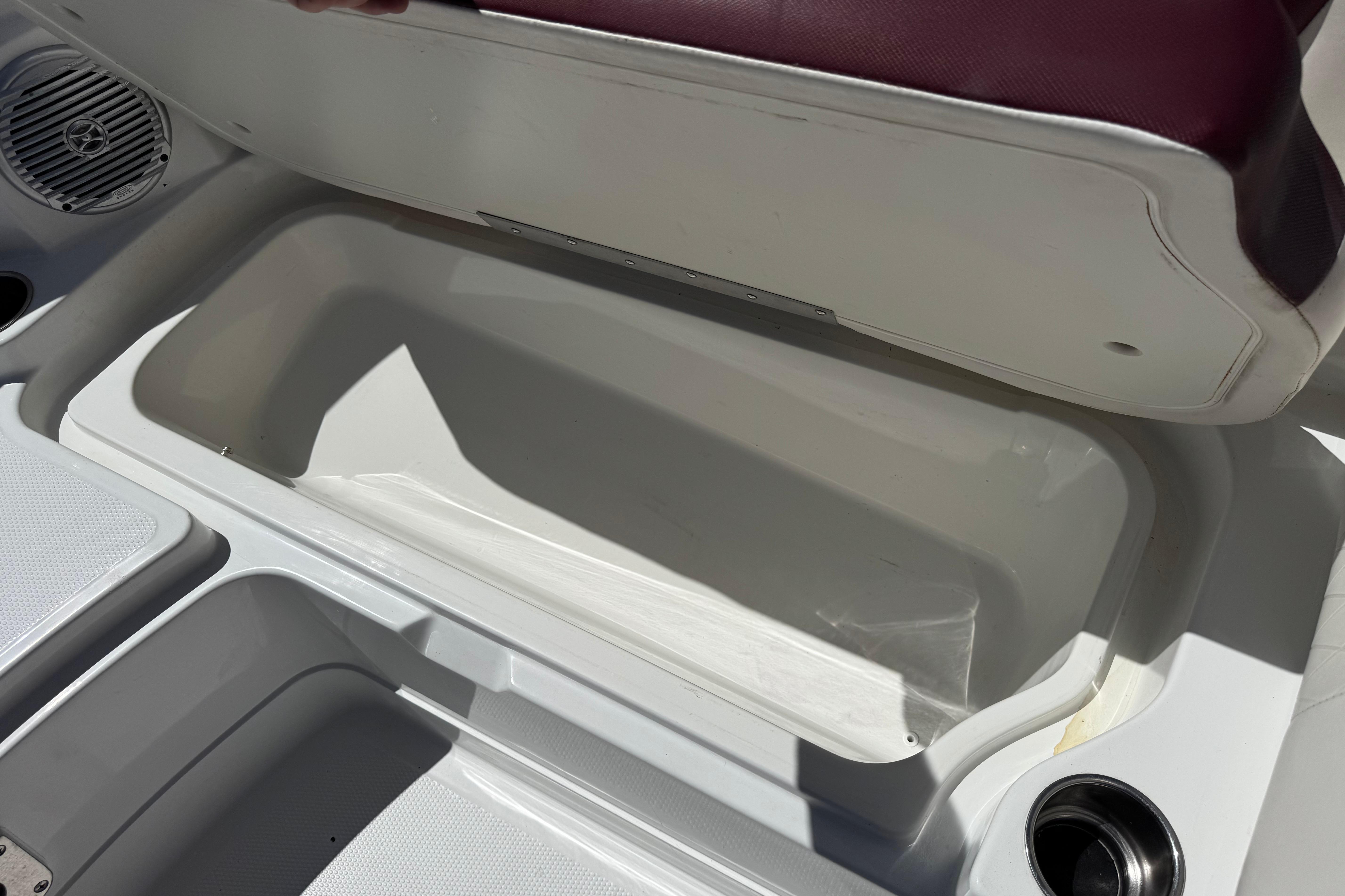 2017 Tahoe 2150 boat storage compartment with open seat and cup holder.