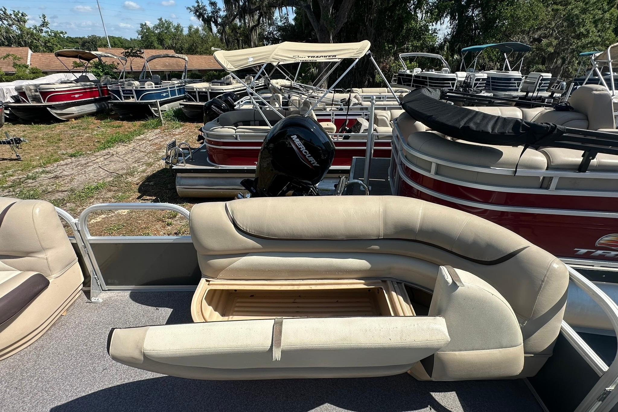 2016 SUNTRACKER Party Barge 20 pontoon boat with open seating storage, surrounded by other boats.