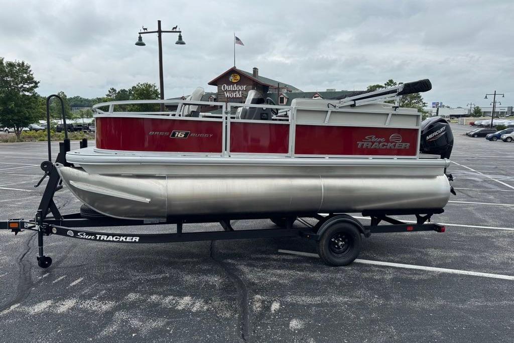 2026 Sun Tracker Bass Buggy 16 XL Select pontoon boat on trailer in parking lot.