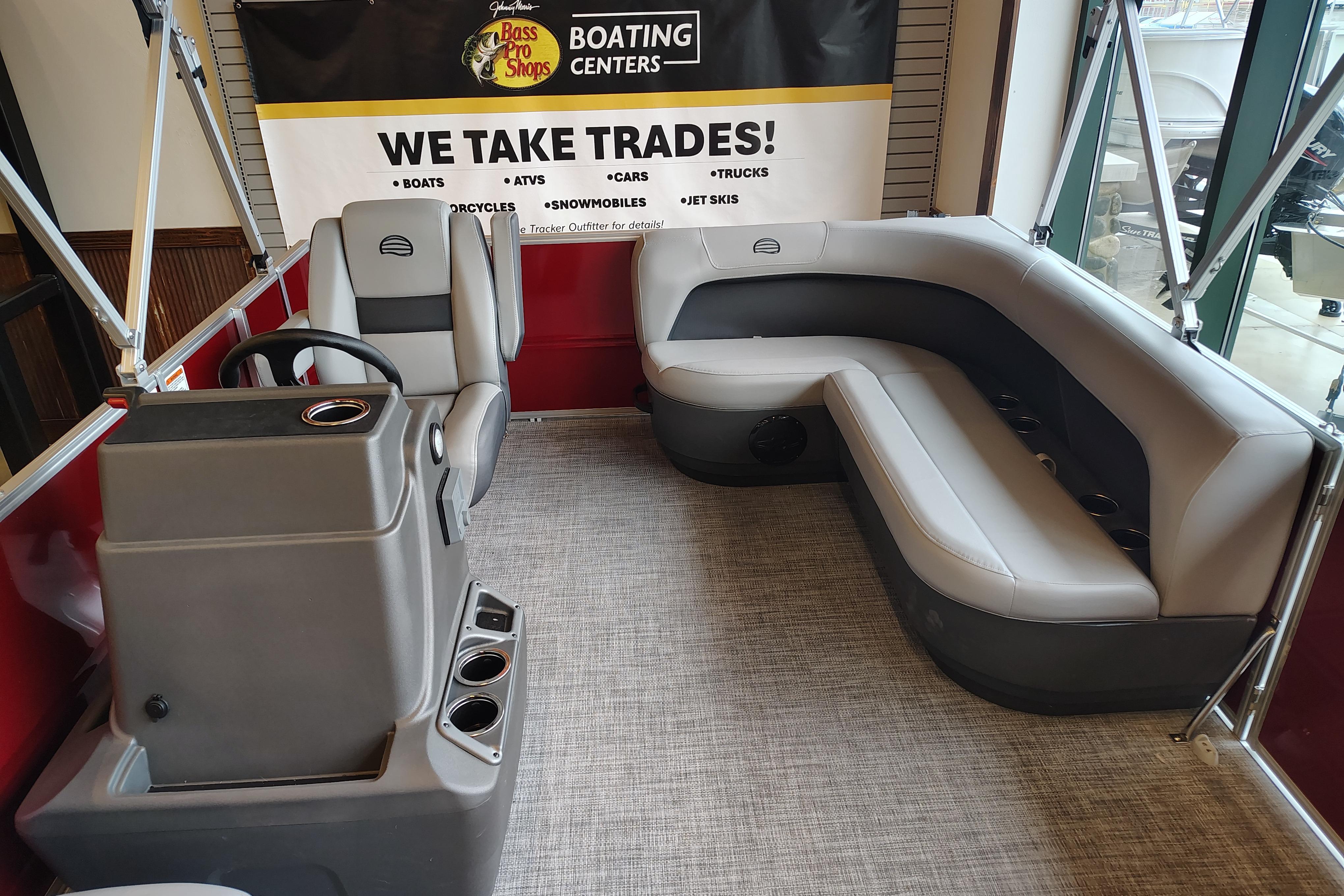 2026 Sun Tracker Party Barge 16 DLX interior with seating and helm, displayed at a boating center.