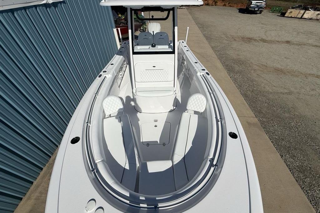 2026 Sportsman Open 232 Center Console boat, white interior, docked beside a blue building.
