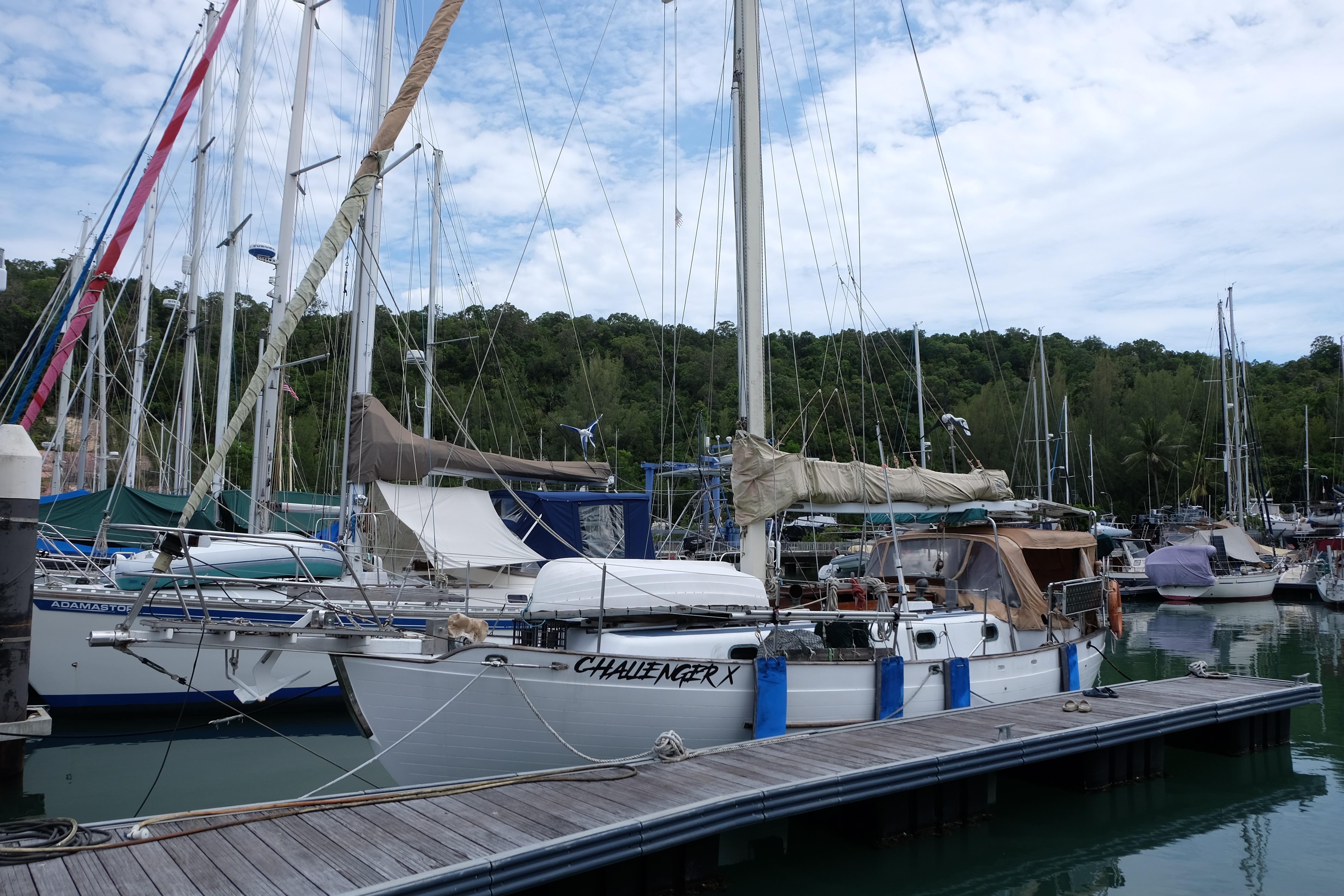 1979 Westwind 35 sailboat docked at a marina with lush greenery in the background.