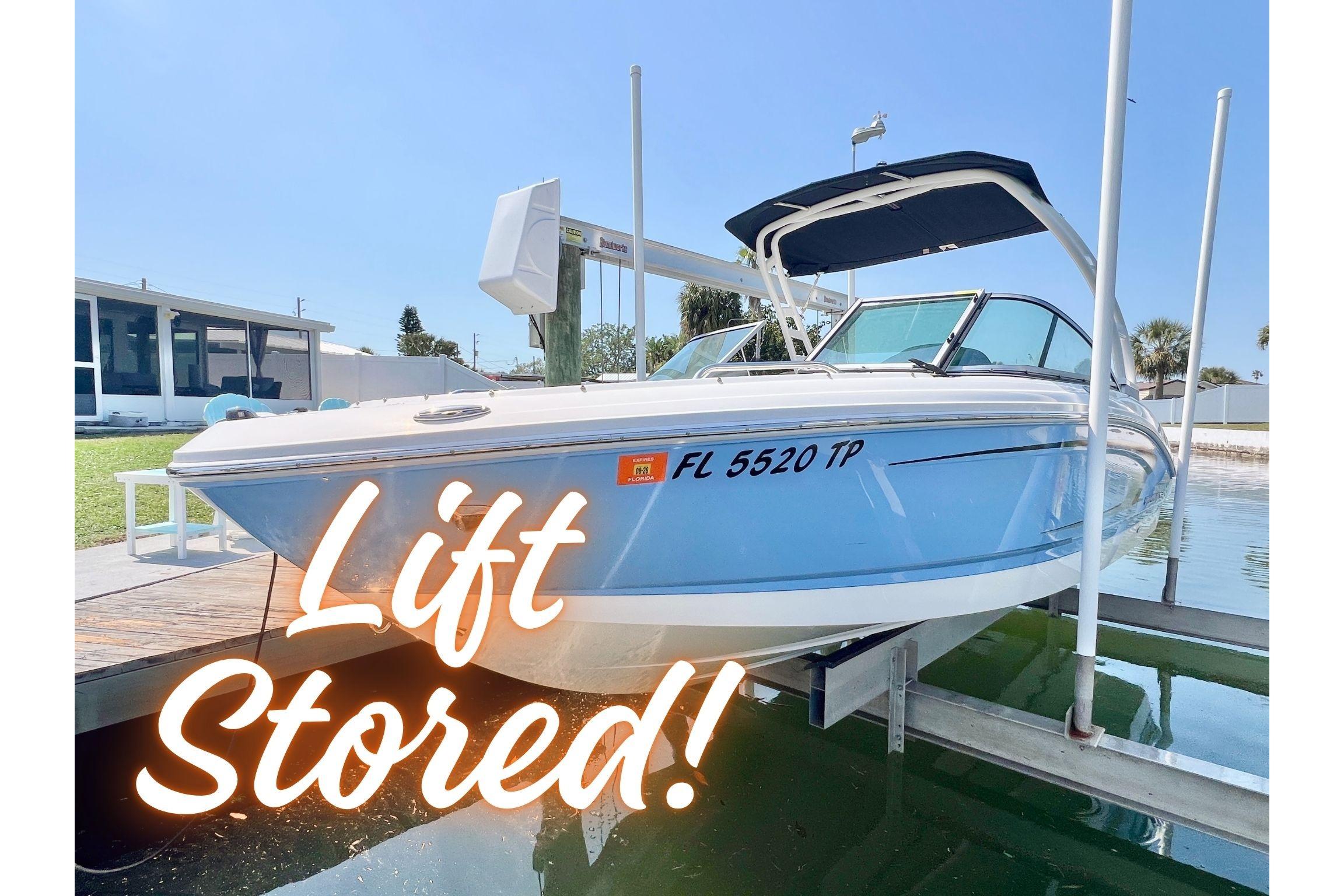 2023 Chaparral 21 SSi OB boat lift-stored, blue hull, docked in sunny marina.