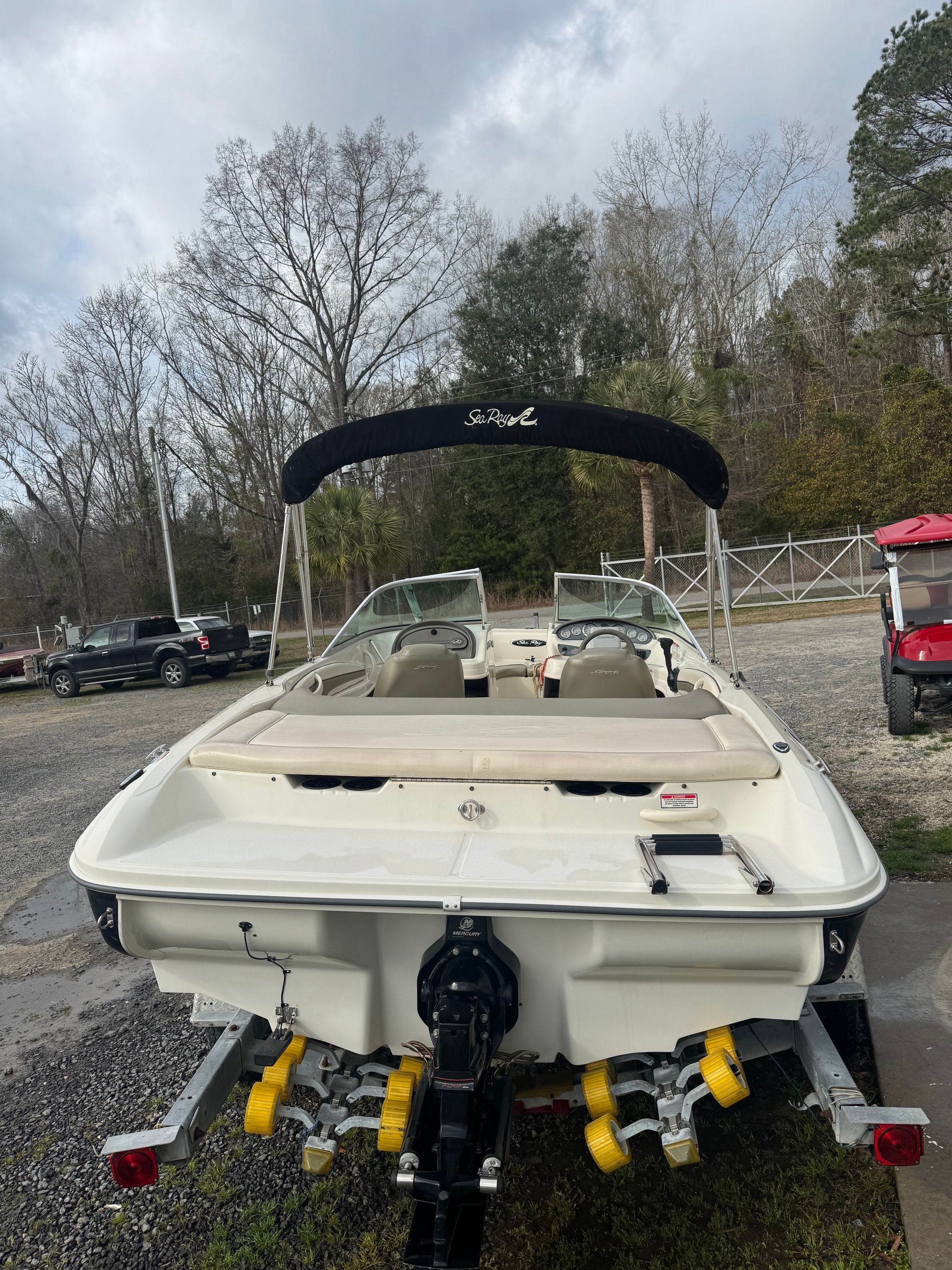 2005 Sea Ray 185 Sport on a trailer, surrounded by trees and vehicles.