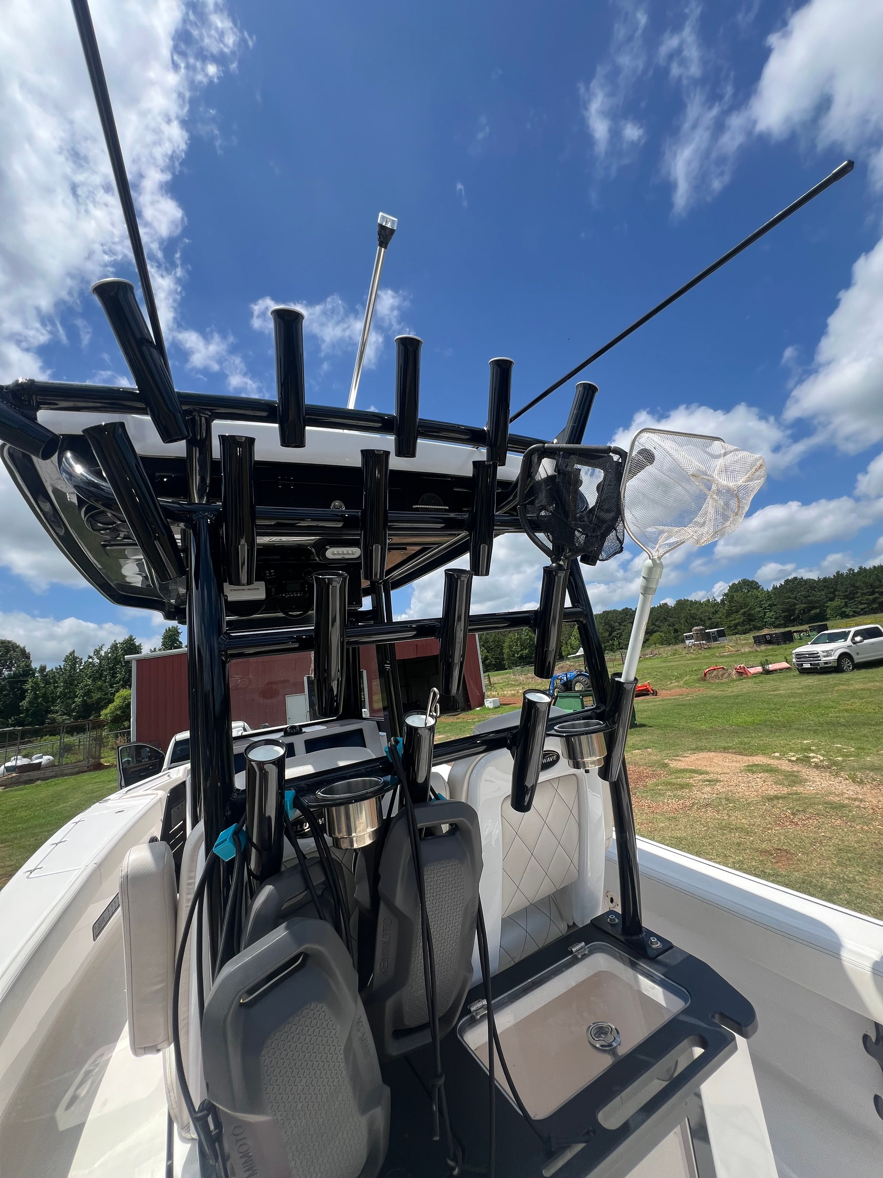 The image shows the cockpit of a 2023 Blue Wave 2800 Makaira boat with fishing rod holders.