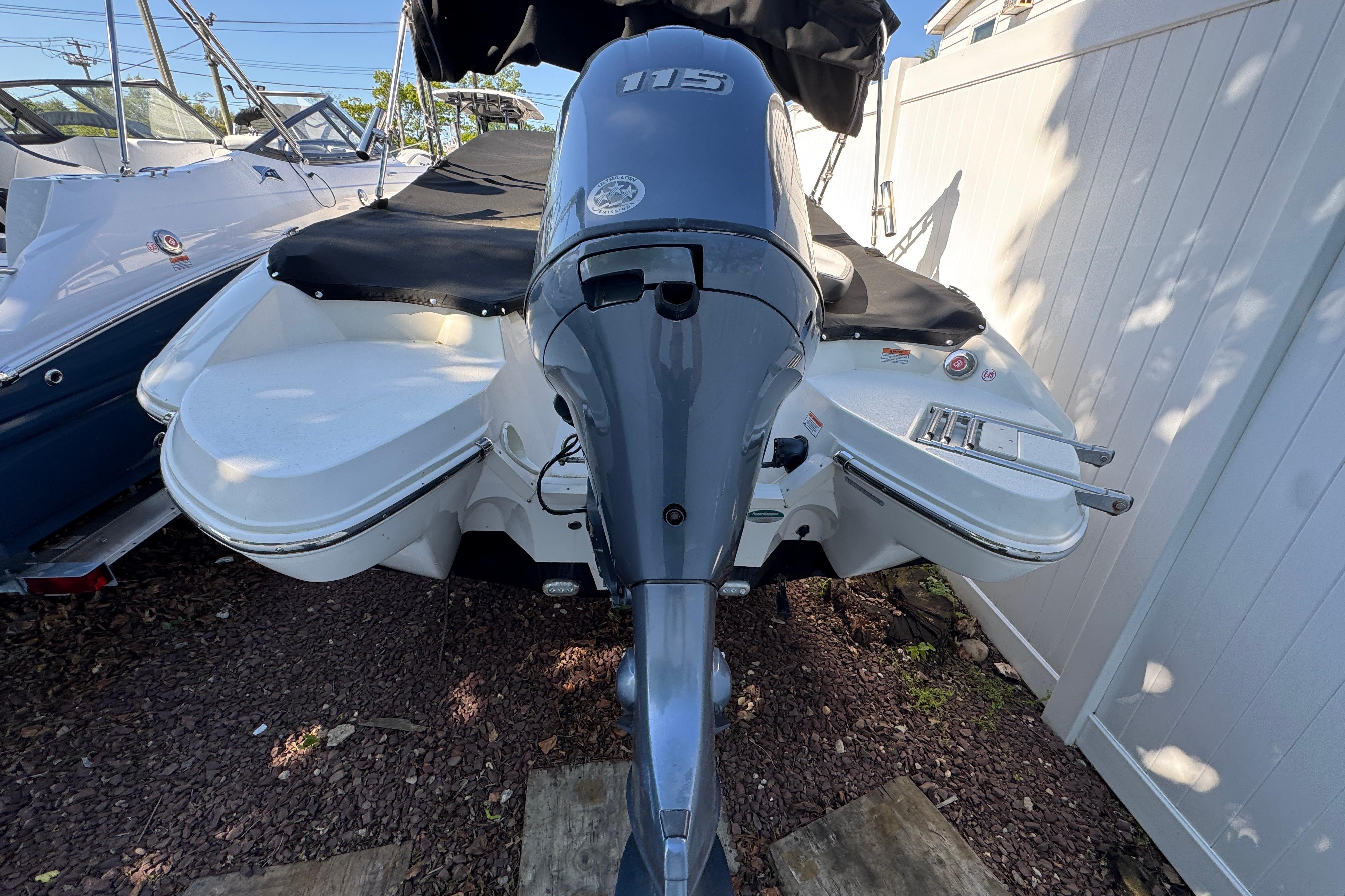 2018 Stingray 204 LR boat with outboard motor, parked on gravel.