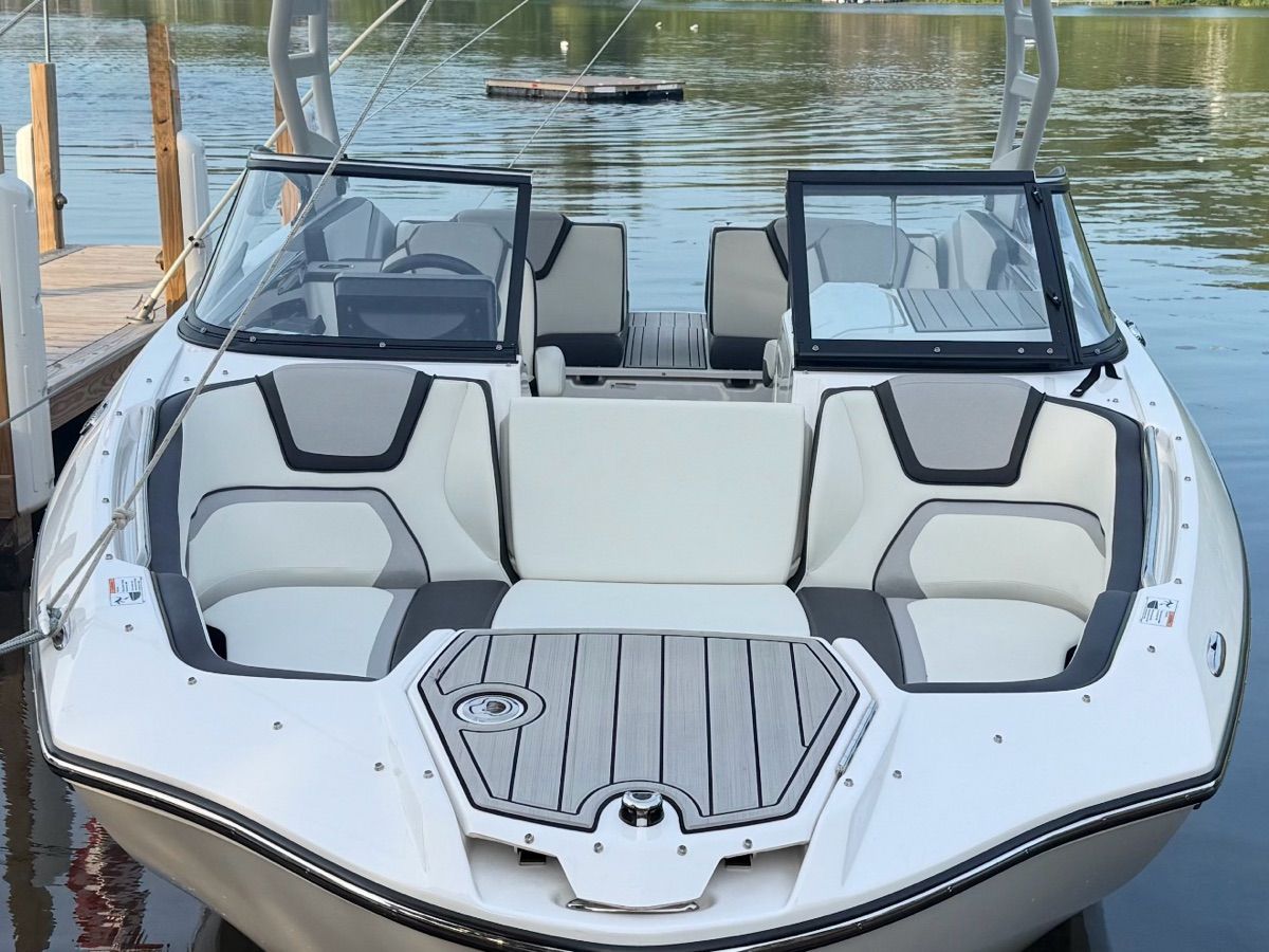 A sleek 2023 Yamaha 252SD boat with modern seating and an open deck by the water.