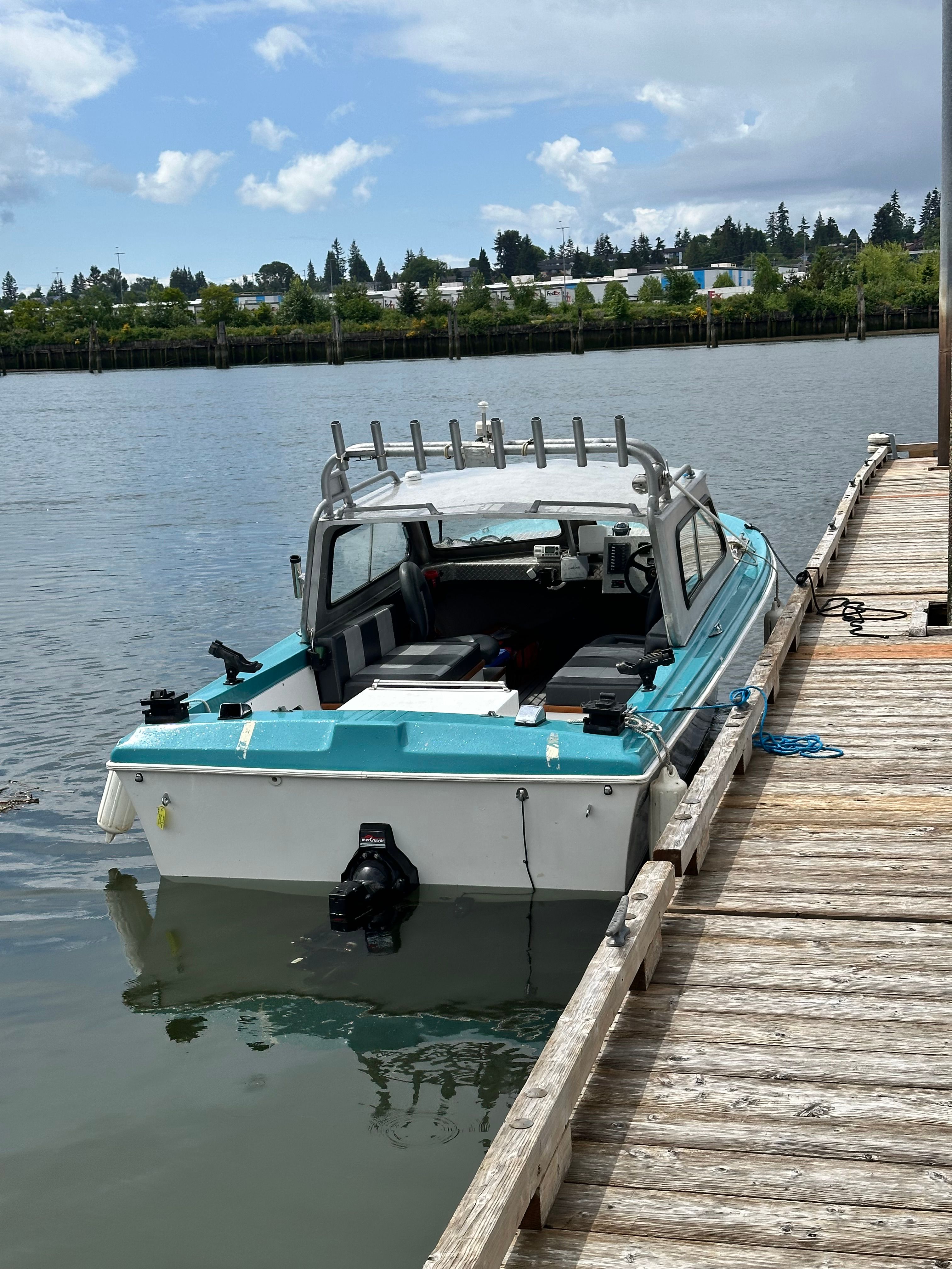 A restored 1967 Fiberform boat docked at a wooden pier. It features a turquoise top.
