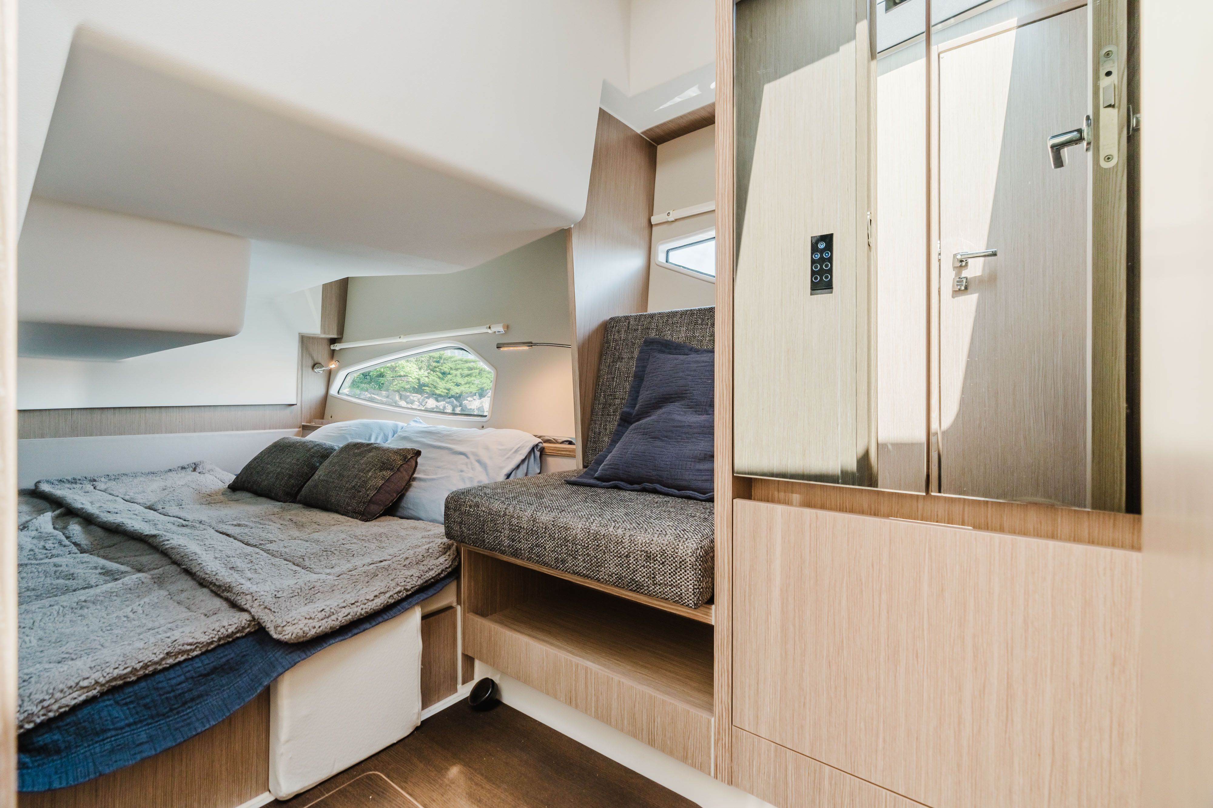 Interior of a modern cabin with bed and seating area, light wood accents, and windows.