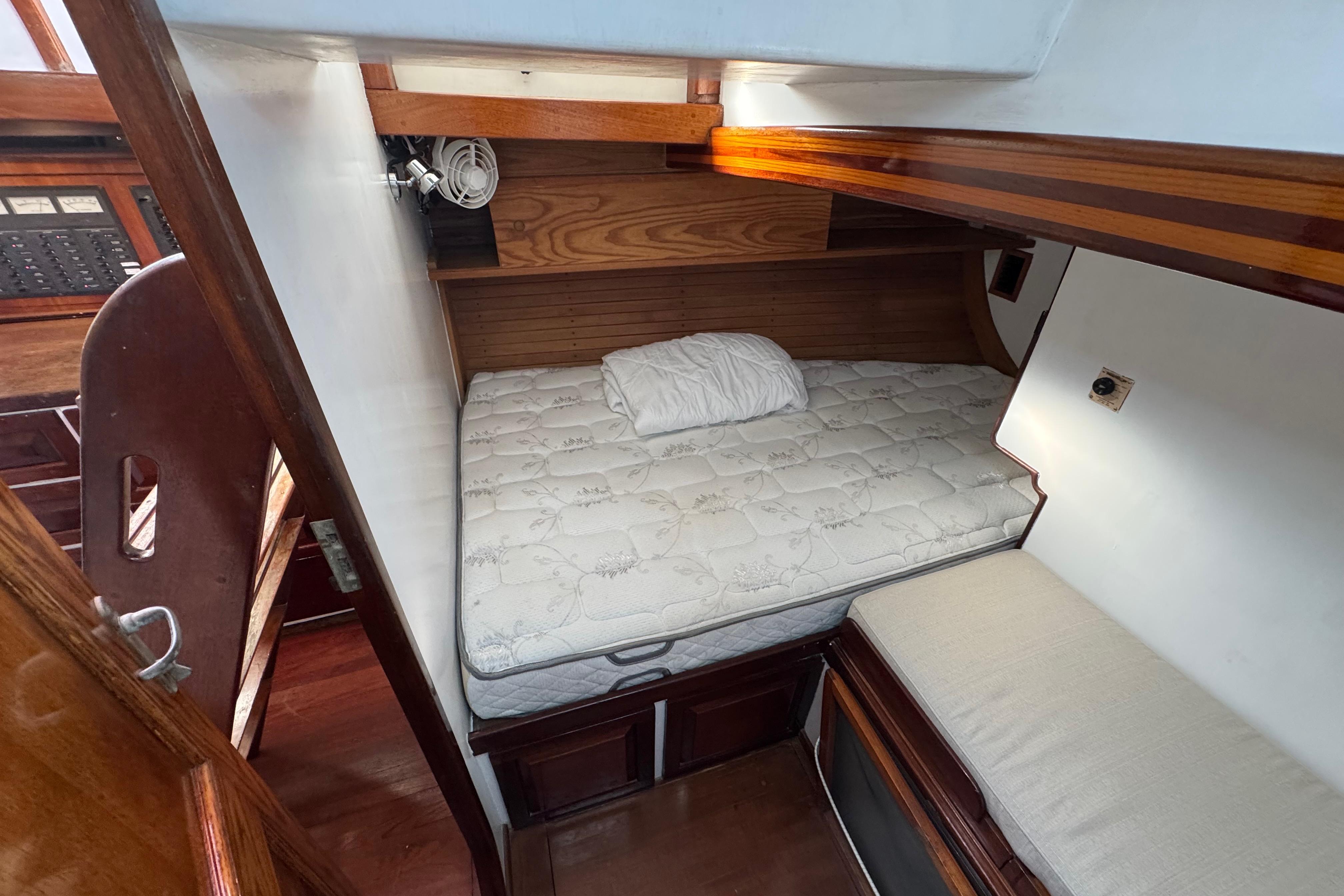 Cozy cabin interior of 1997 Creekmore Cutter sailboat with bed and wooden accents.
