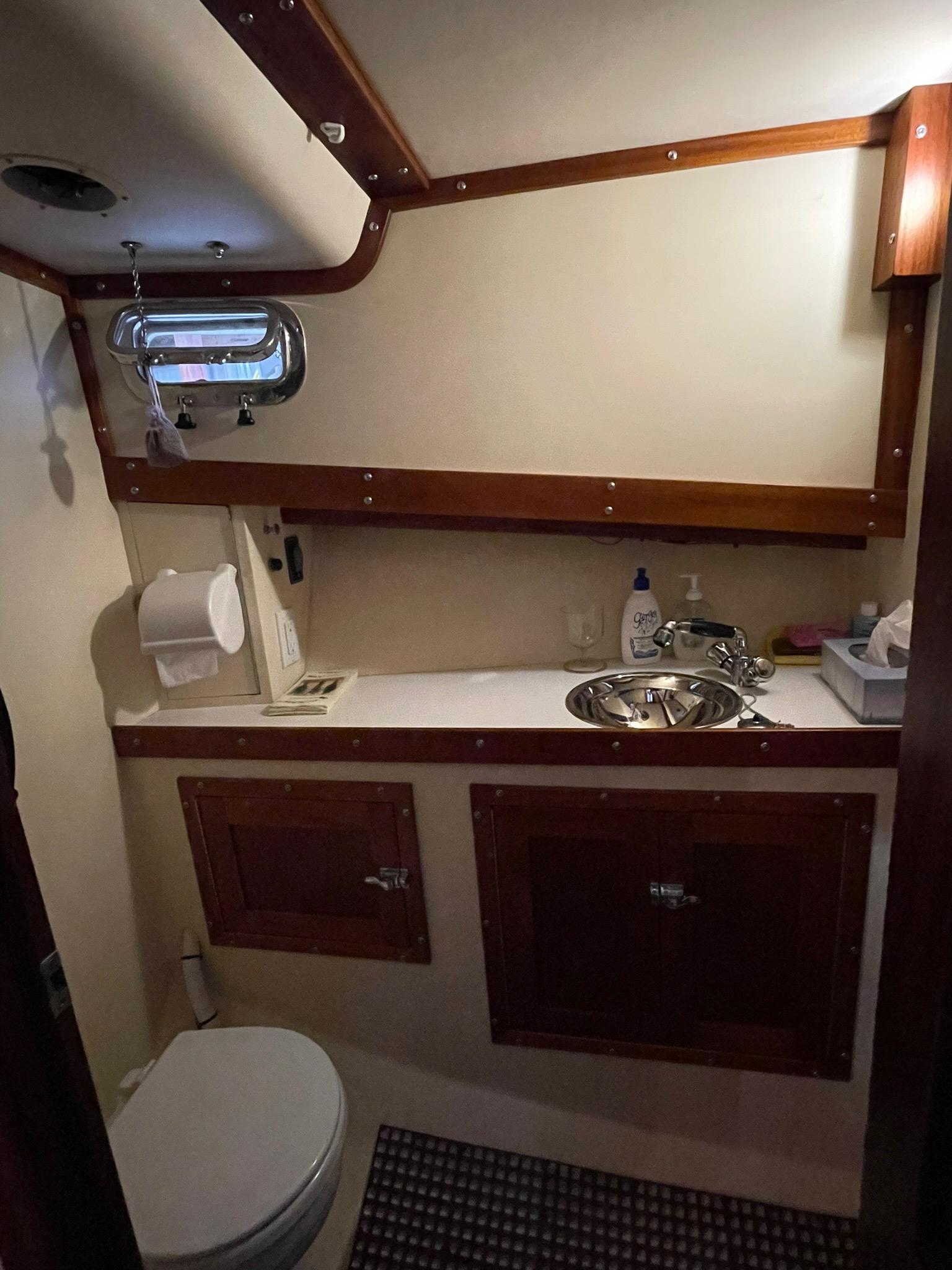 Compact bathroom in a 2002 Jarvis Newman 32 boat, featuring a sink and toilet.