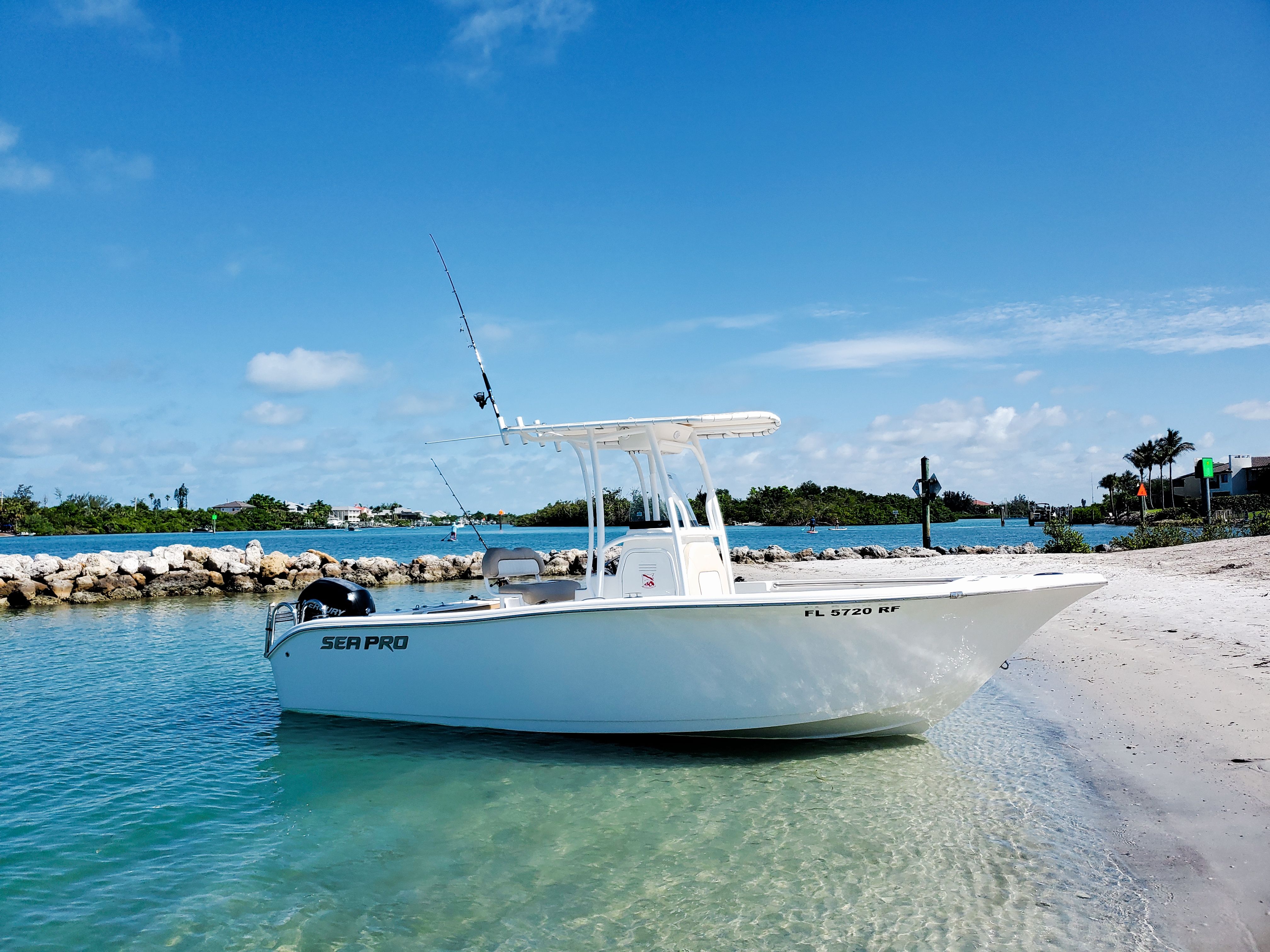 A 2017 Sea Pro 219 Center Console boat is beached on clear blue water.