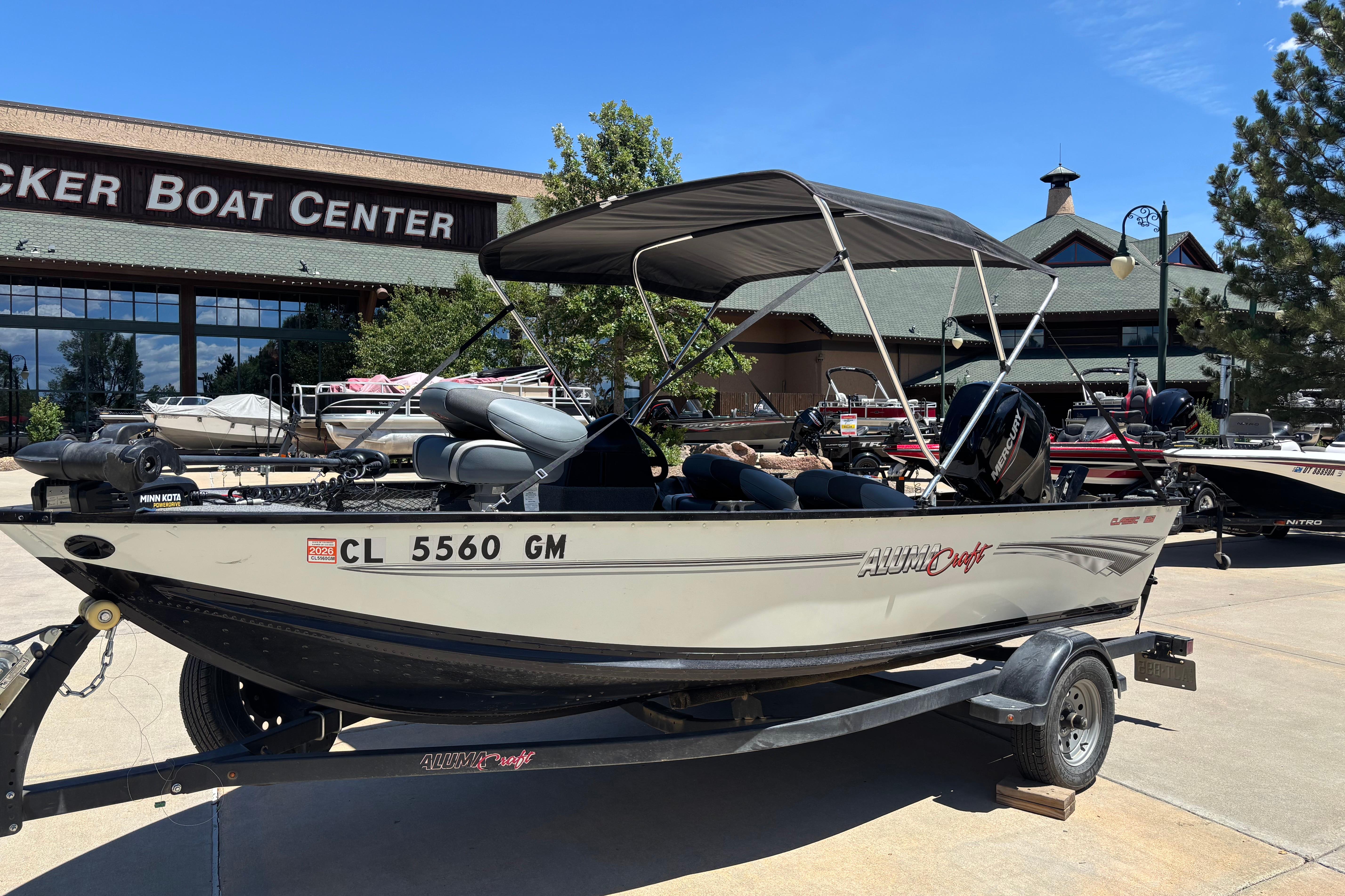 2021 Alumacraft Classic 165 boat with canopy at a boat center, parked on a trailer.