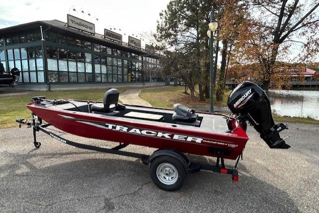 2025 Tracker Panfish 17 boat with Mercury engine, parked near a modern building and trees.
