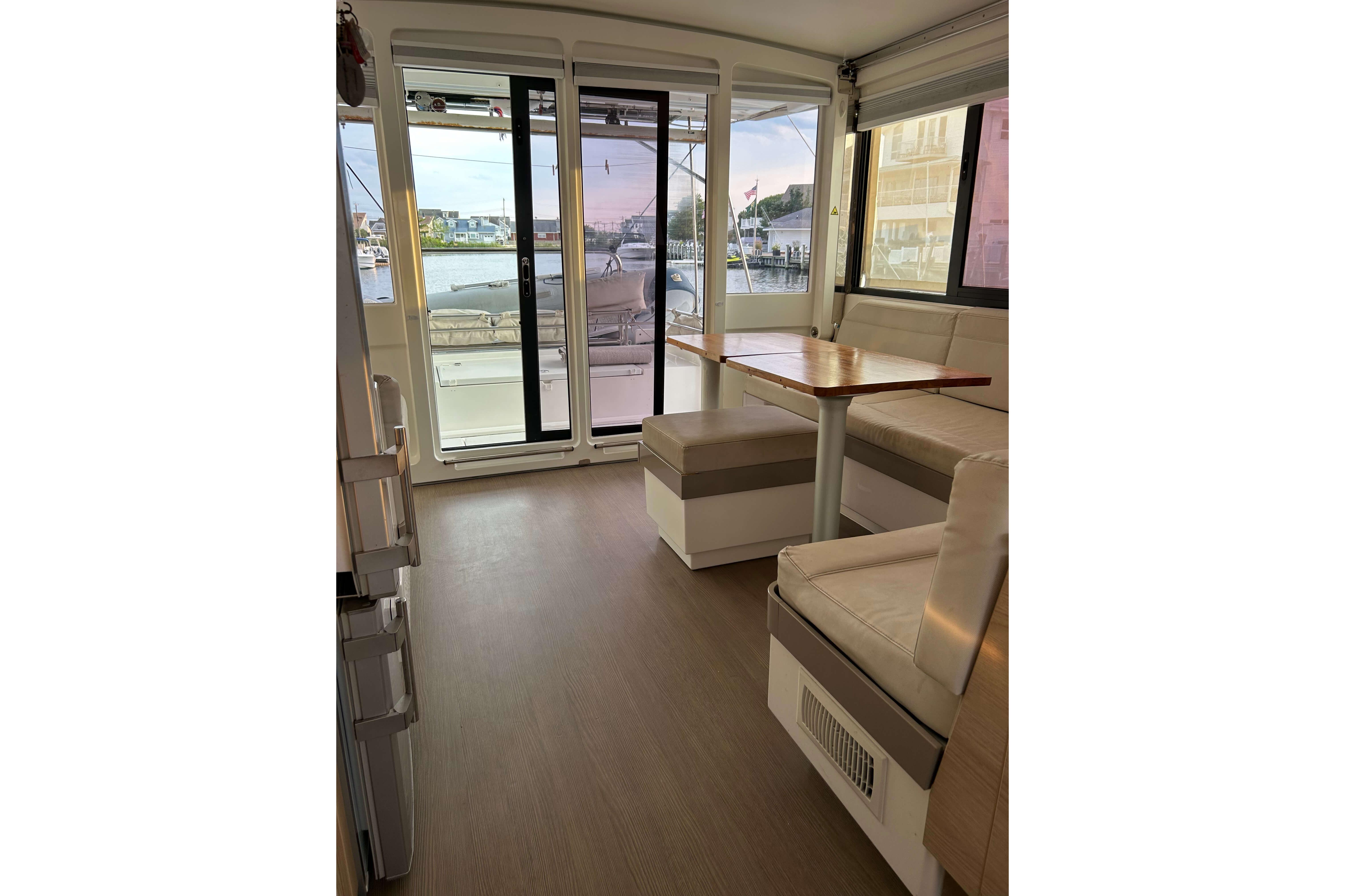 Interior of 2018 Bali 4.1 catamaran with seating and table, overlooking marina.