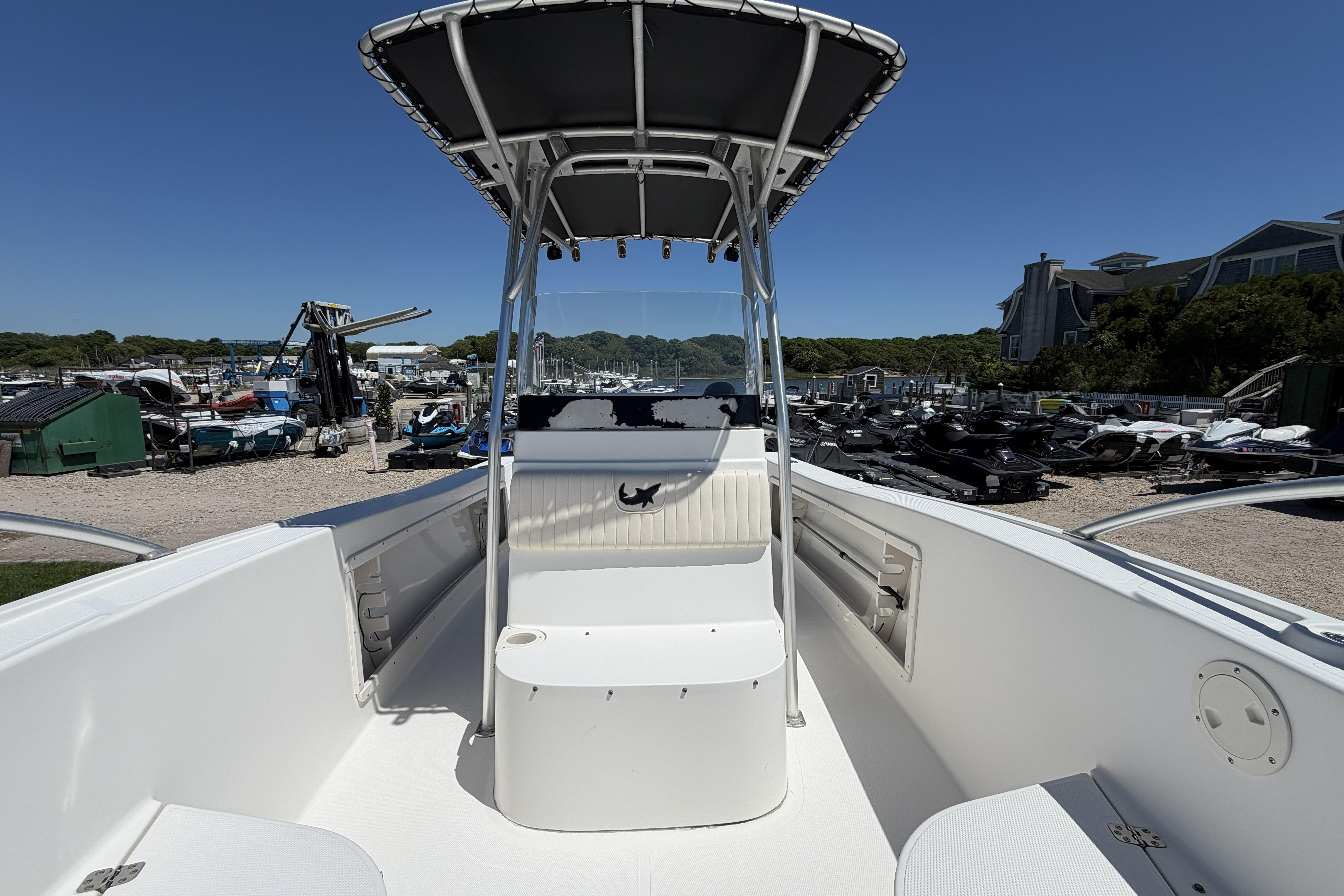 2006 Mako 212 Center Console boat with T-top, docked in a marina under clear blue skies.