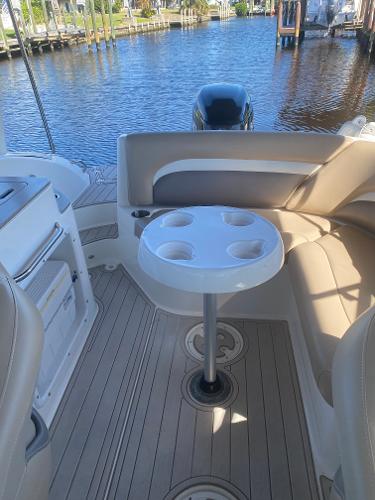 2015 Hurricane SunDeck 2400 OB boat interior with seating and table, docked by the water.