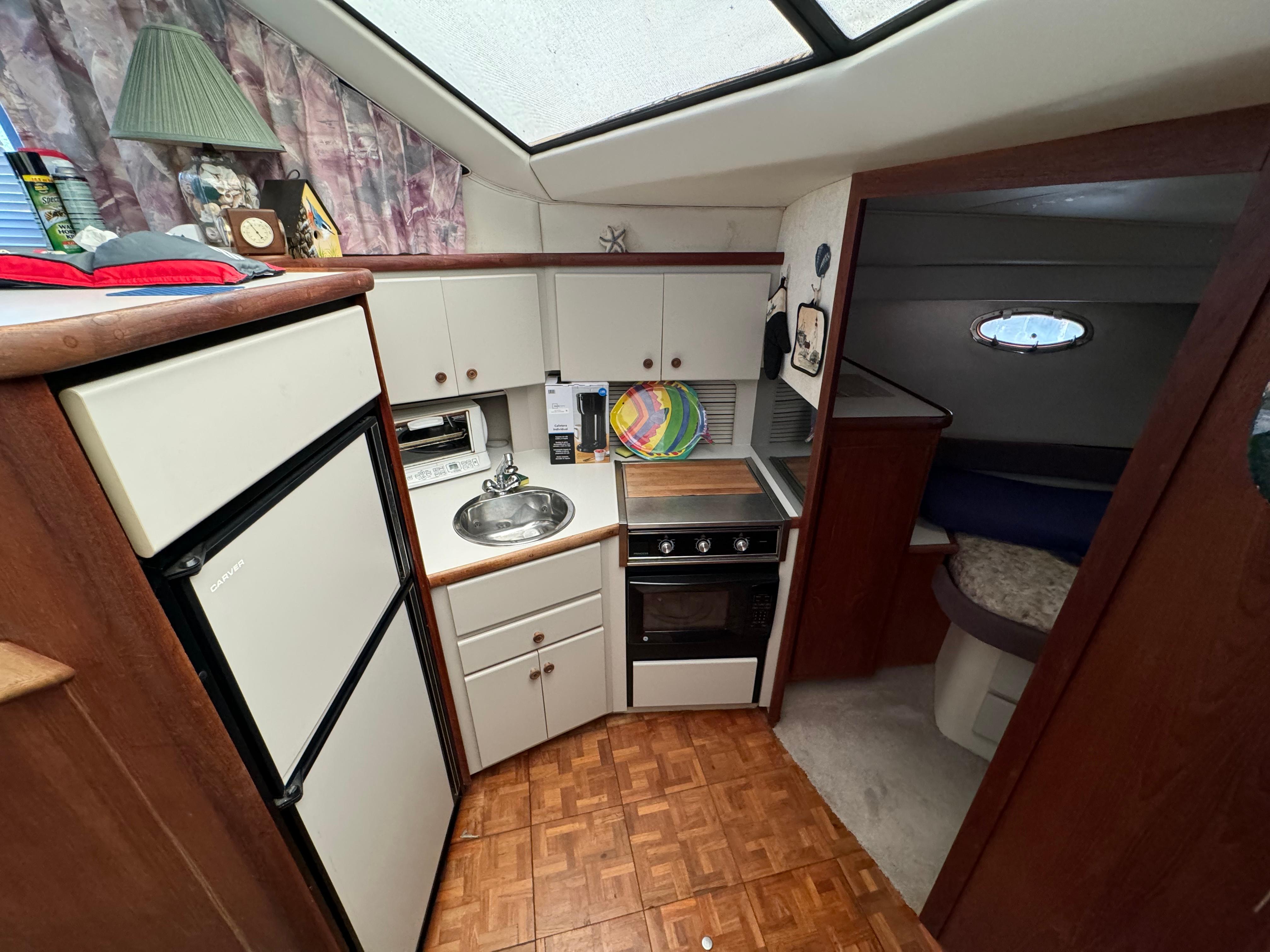 1991 Carver 33 Aft Cabin kitchen with stove, sink, and refrigerator. Cozy and functional design.